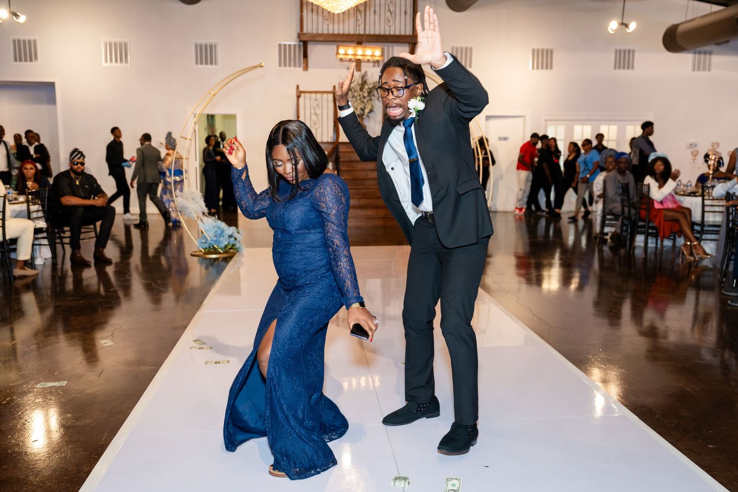 People mingling and dancing on a white floor in an art gallery or event space with bright lighting.