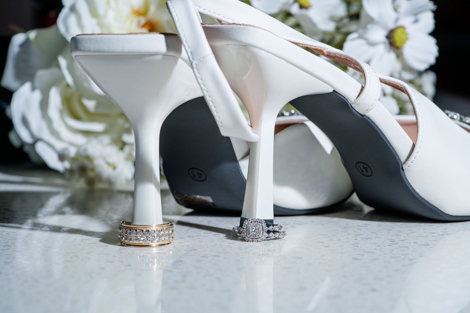 Close-up of elegant white bridal shoes with crystal embellishments.
