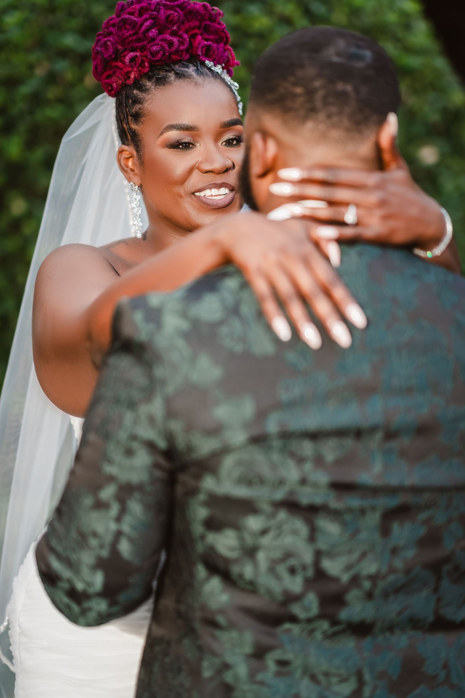 A bride wearing a red floral crown shares a tender moment with her groom during outdoor wedding photos.