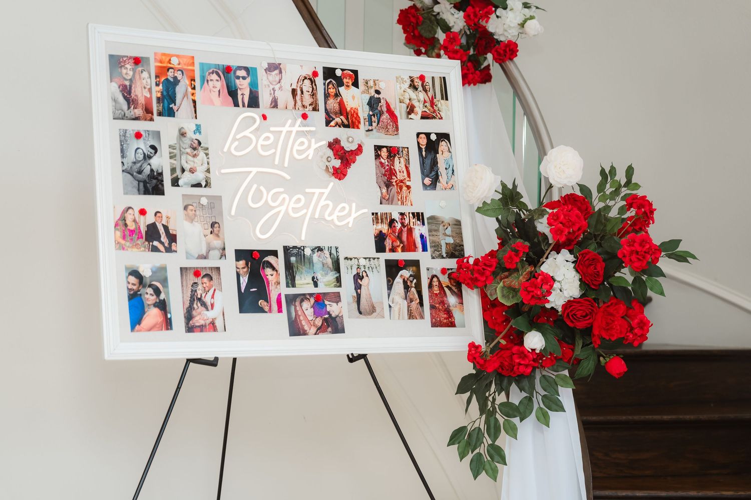 White photo display boards decorated with red roses showcase a collection of photographs at an event.