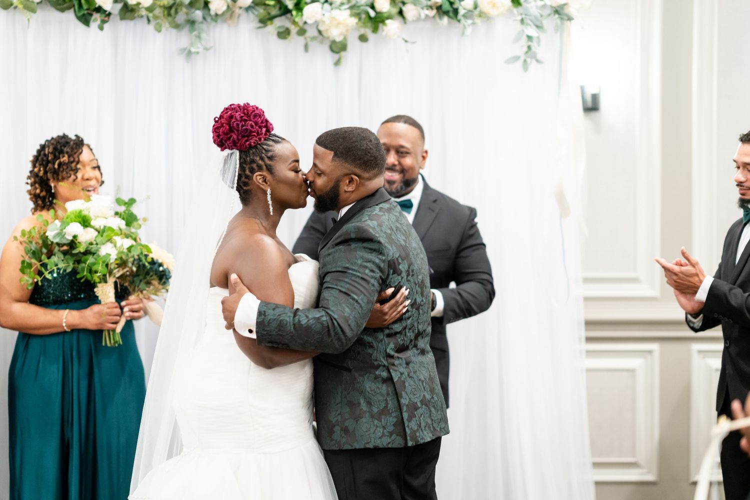 Wedding party members in teal dresses and dark suits embrace during celebration moments.
