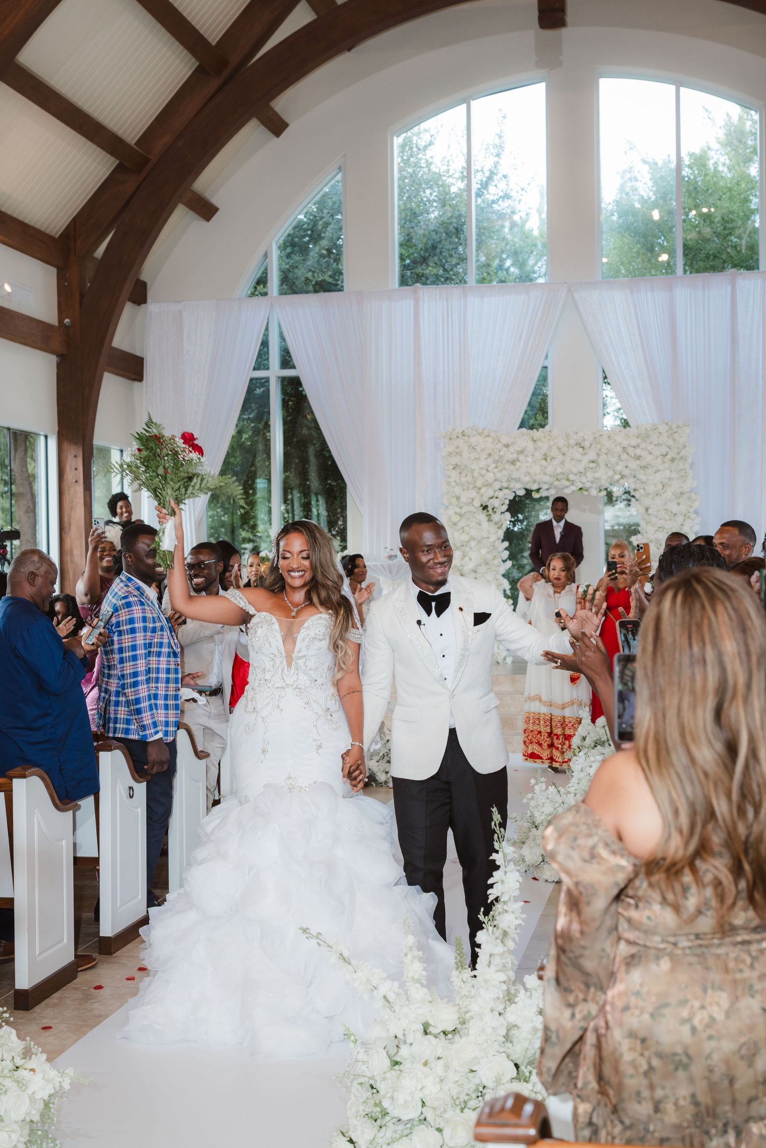 Wedding ceremony in a chapel with exposed wooden beams and large windows.