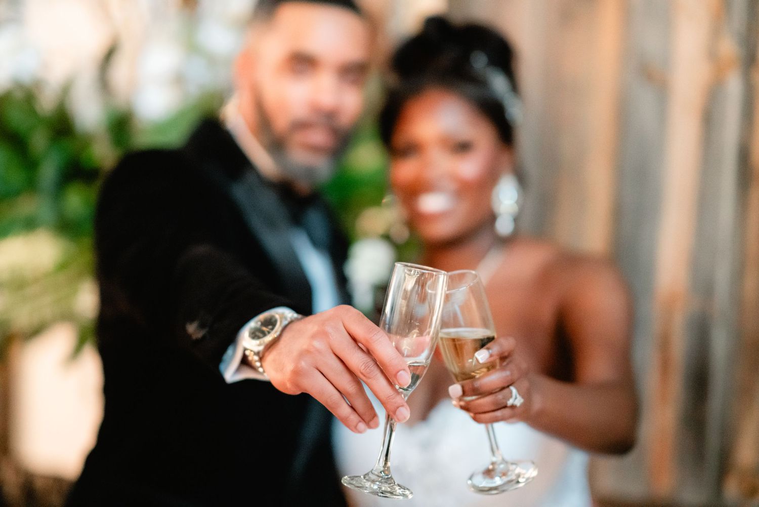 Wedding couple toasting with champagne glasses under warm lighting at an elegant reception.
