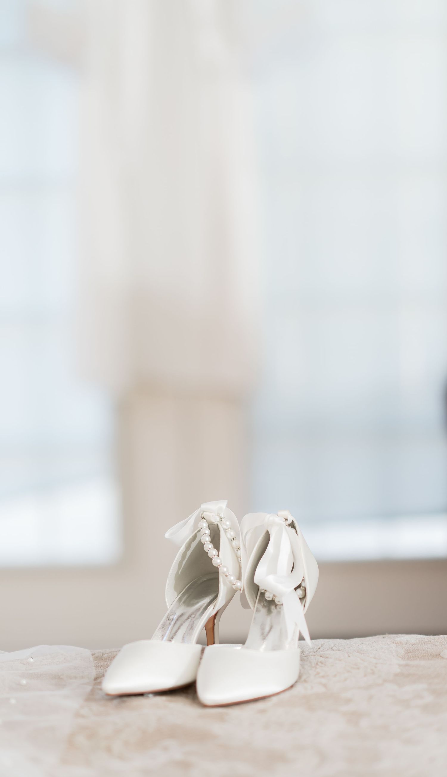 Elegant white bridal shoes photographed in soft, dreamy lighting.