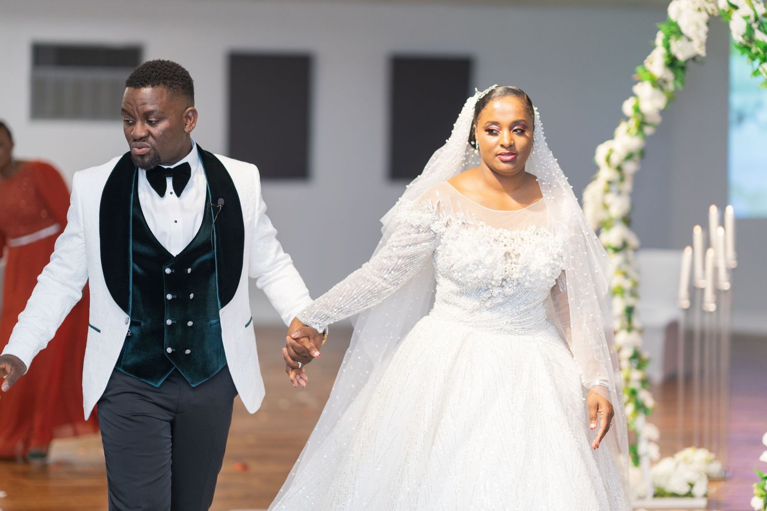 Elegant wedding ceremony captured in a modern indoor venue with decorative floral arrangements.