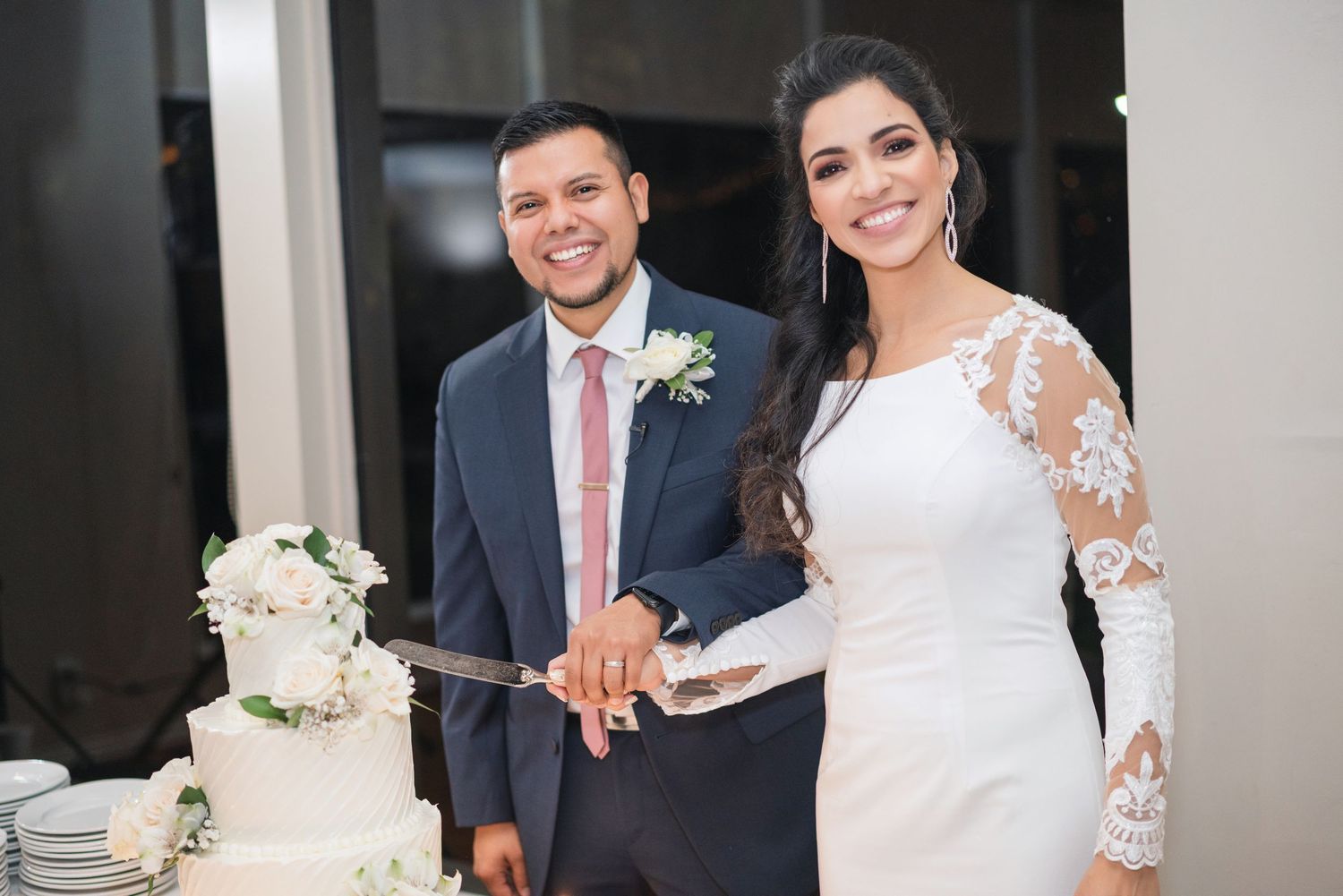 Elegant white wedding cake displayed at reception with floral decorations.
