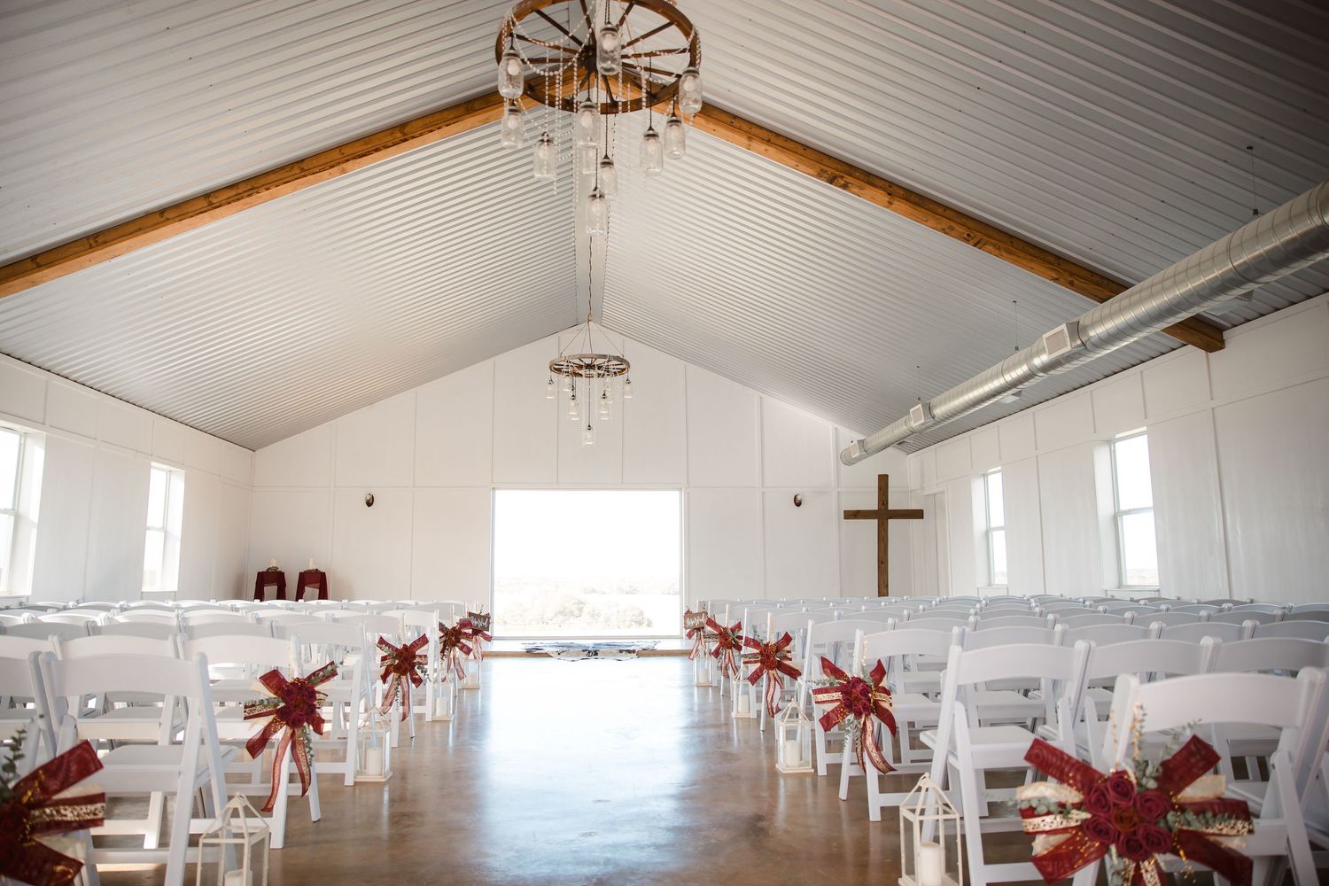 White church interior with wooden beams, cross on wall, and red poinsettia decorations.