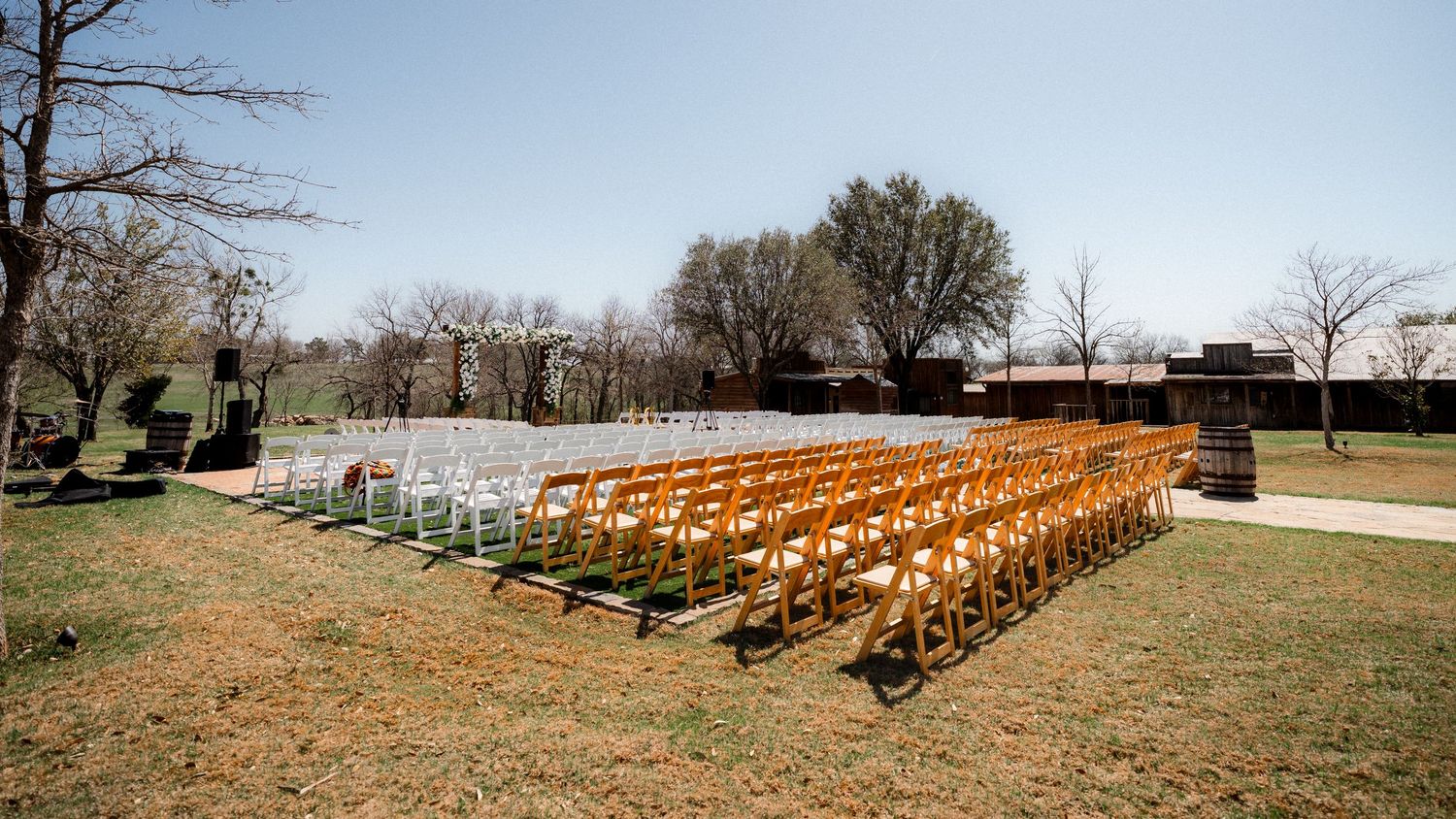 Panoramic view of wooden chairs arranged in rows for an outdoor wedding ceremony.