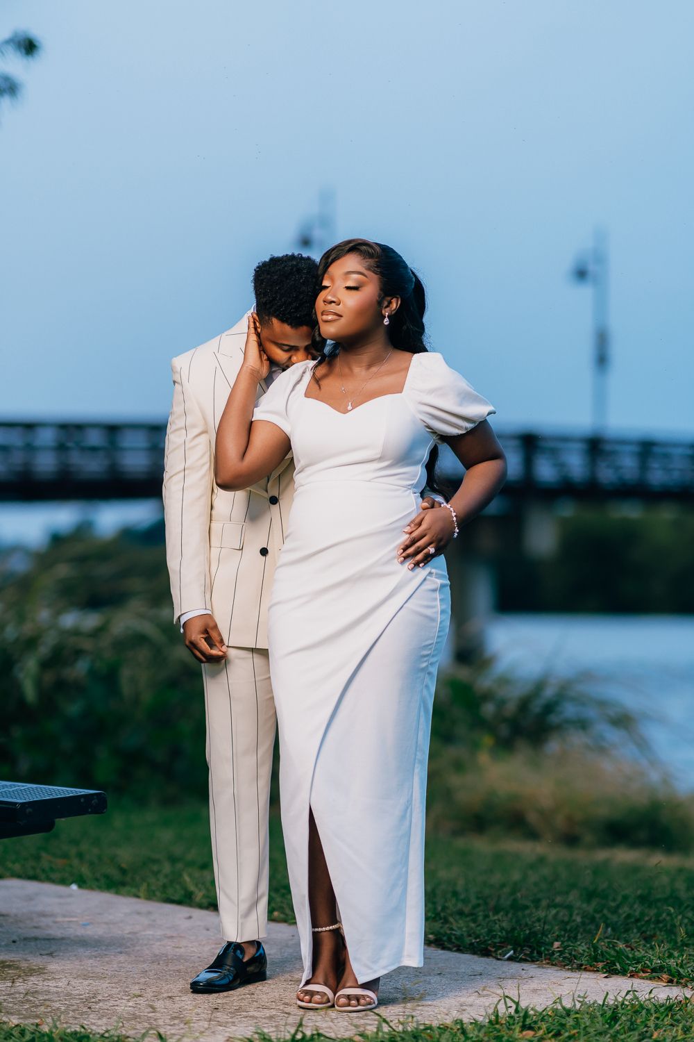 Couple sharing an intimate moment outdoors in coordinated white and cream colored formal attire.