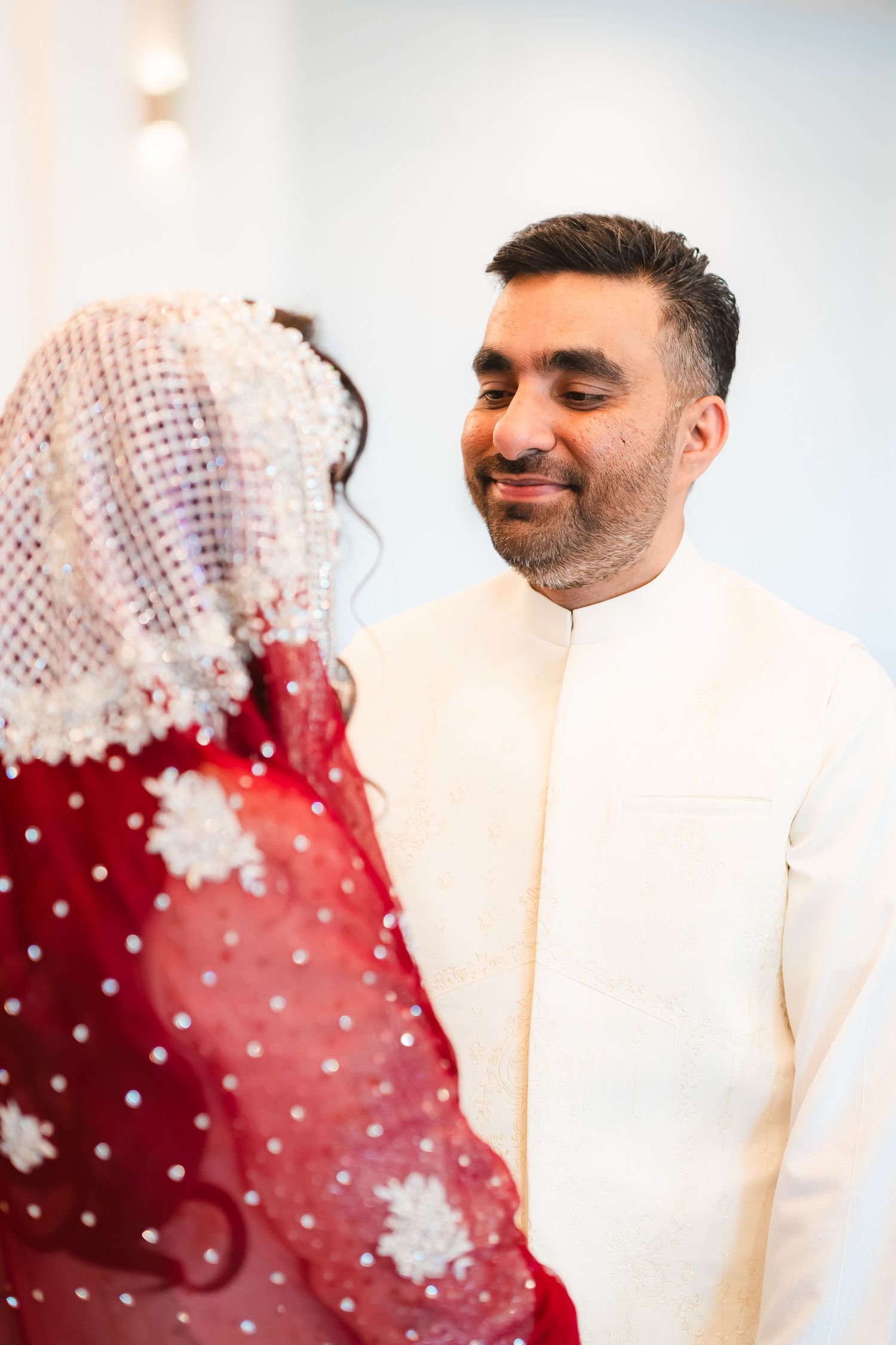 Couple in traditional South Asian wedding attire sharing a moment together.