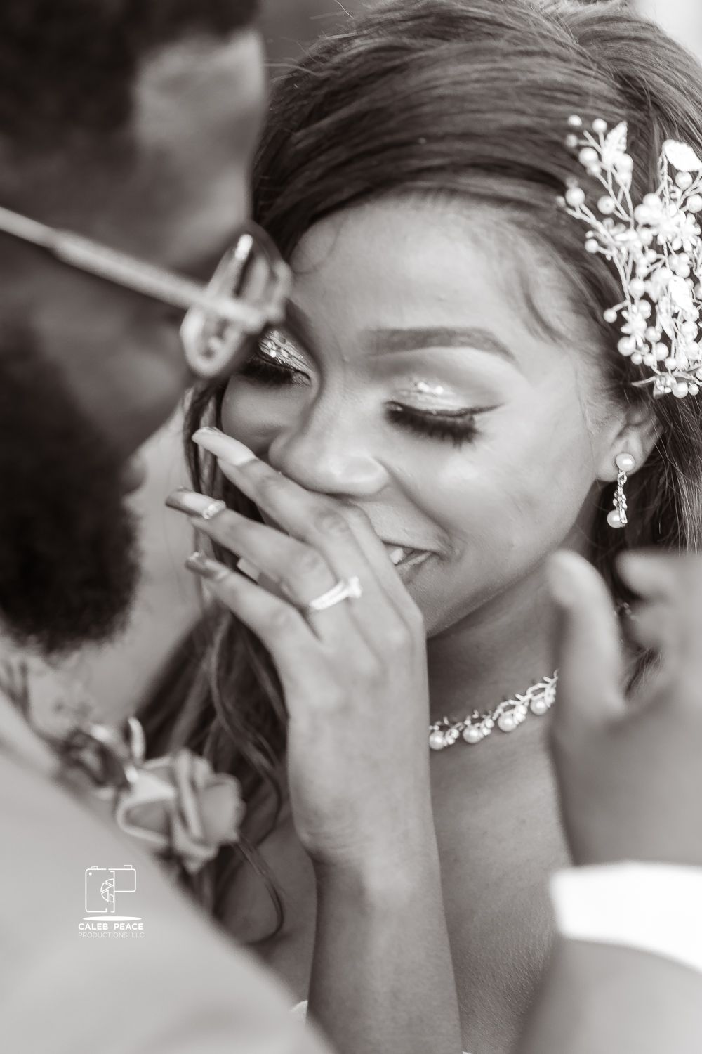 Candid black and white wedding photo showing joyful emotional moment between bride and groom during ceremony.