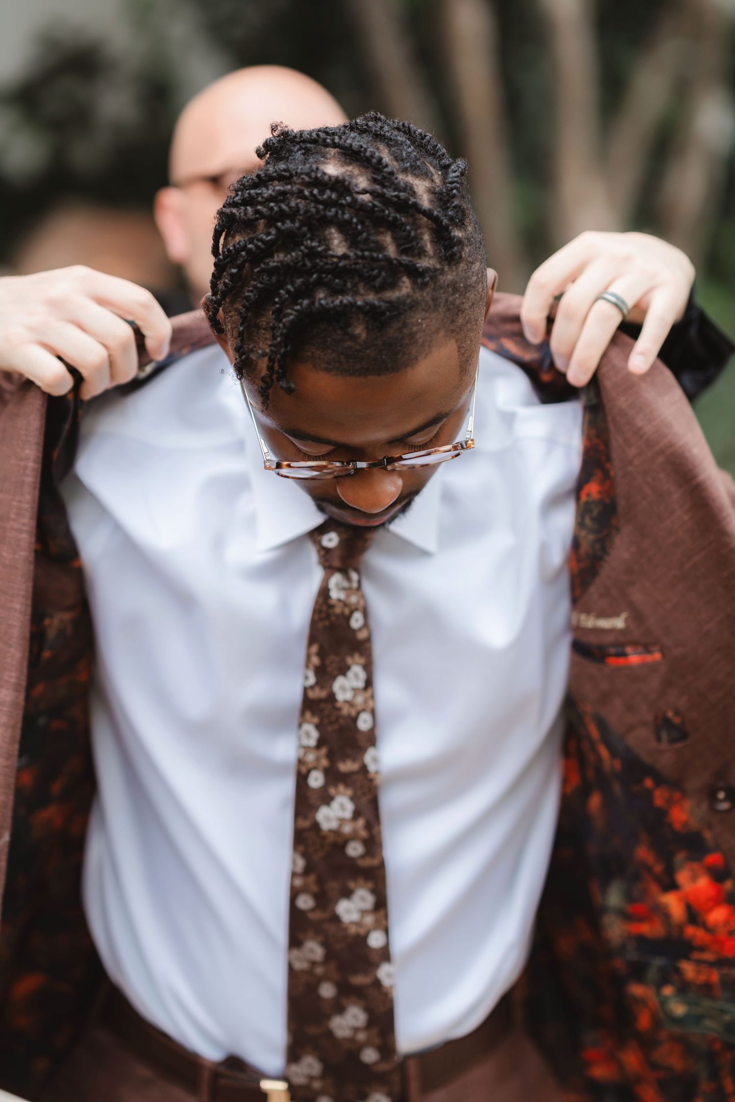 Close-up sequence showing detailed braided hairstyling process against white shirt and brown tie.