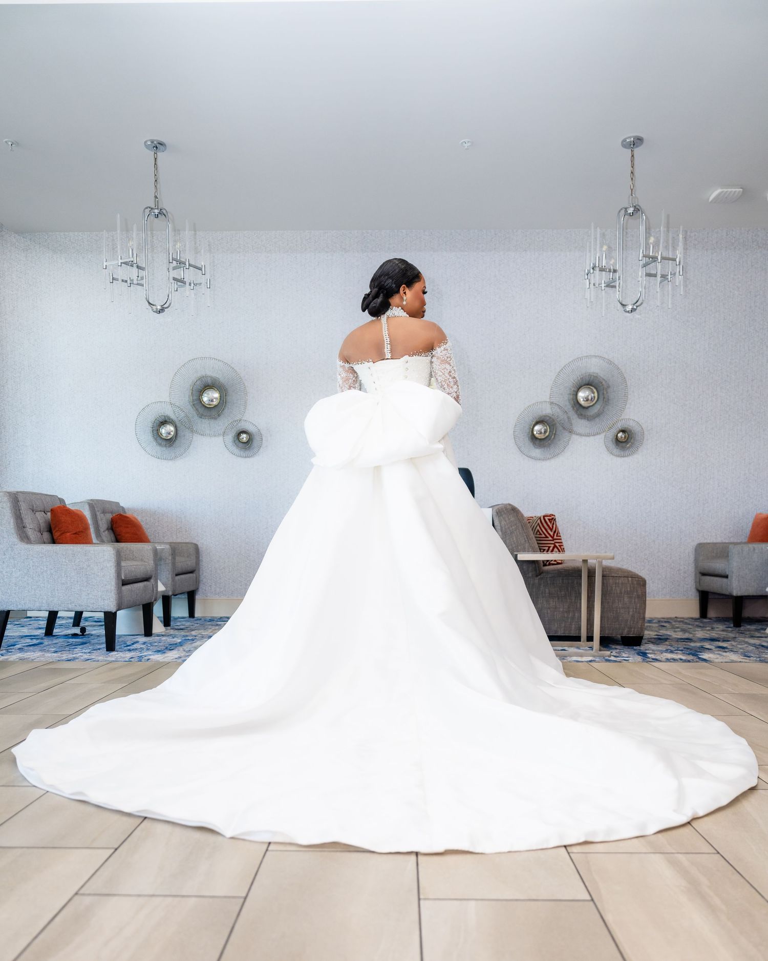A stunning white wedding gown with a dramatic cathedral train photographed in an elegant room with modern chandeliers.