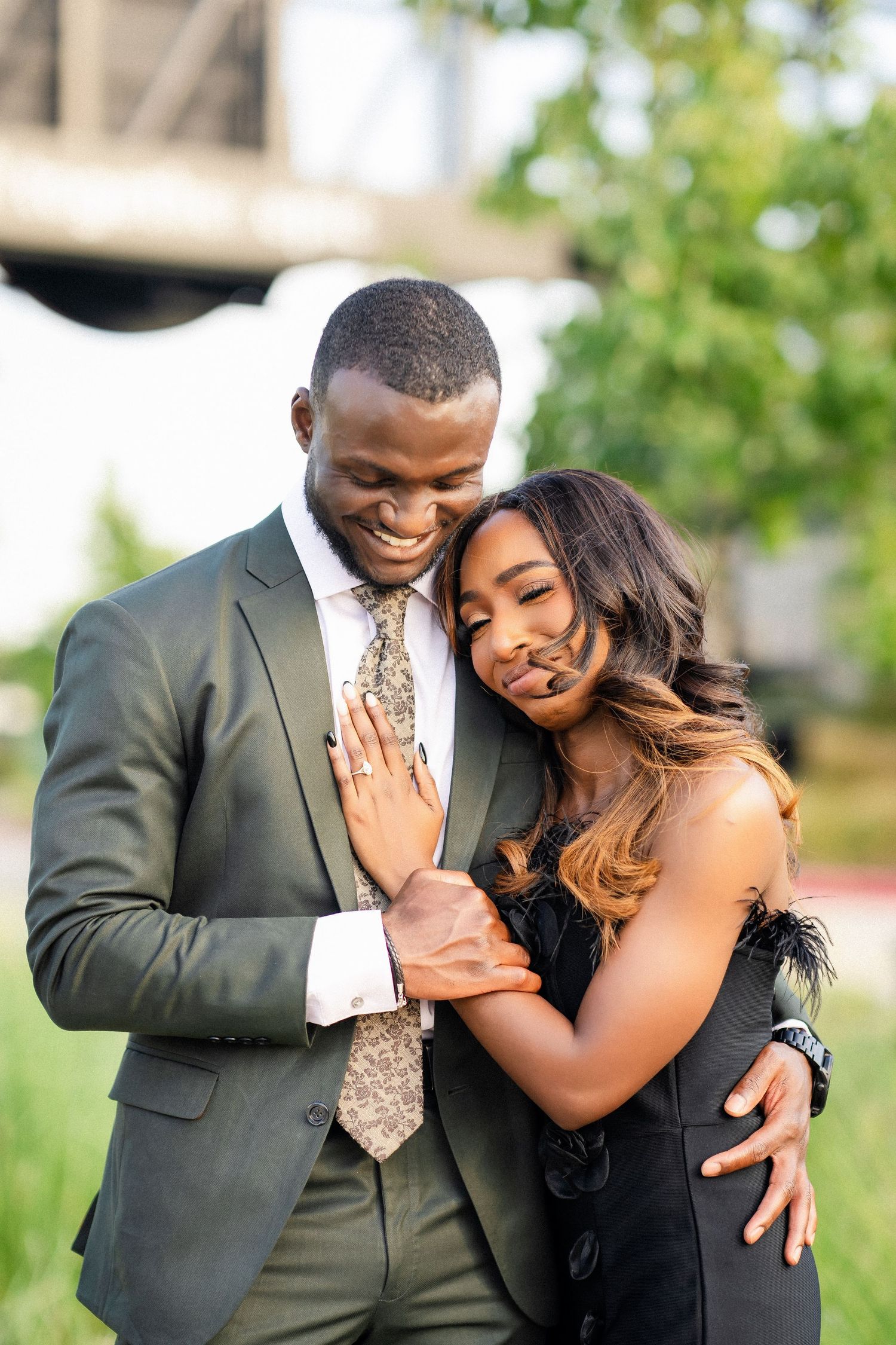 A joyful couple in formal wear share loving embraces while showing off an engagement ring.