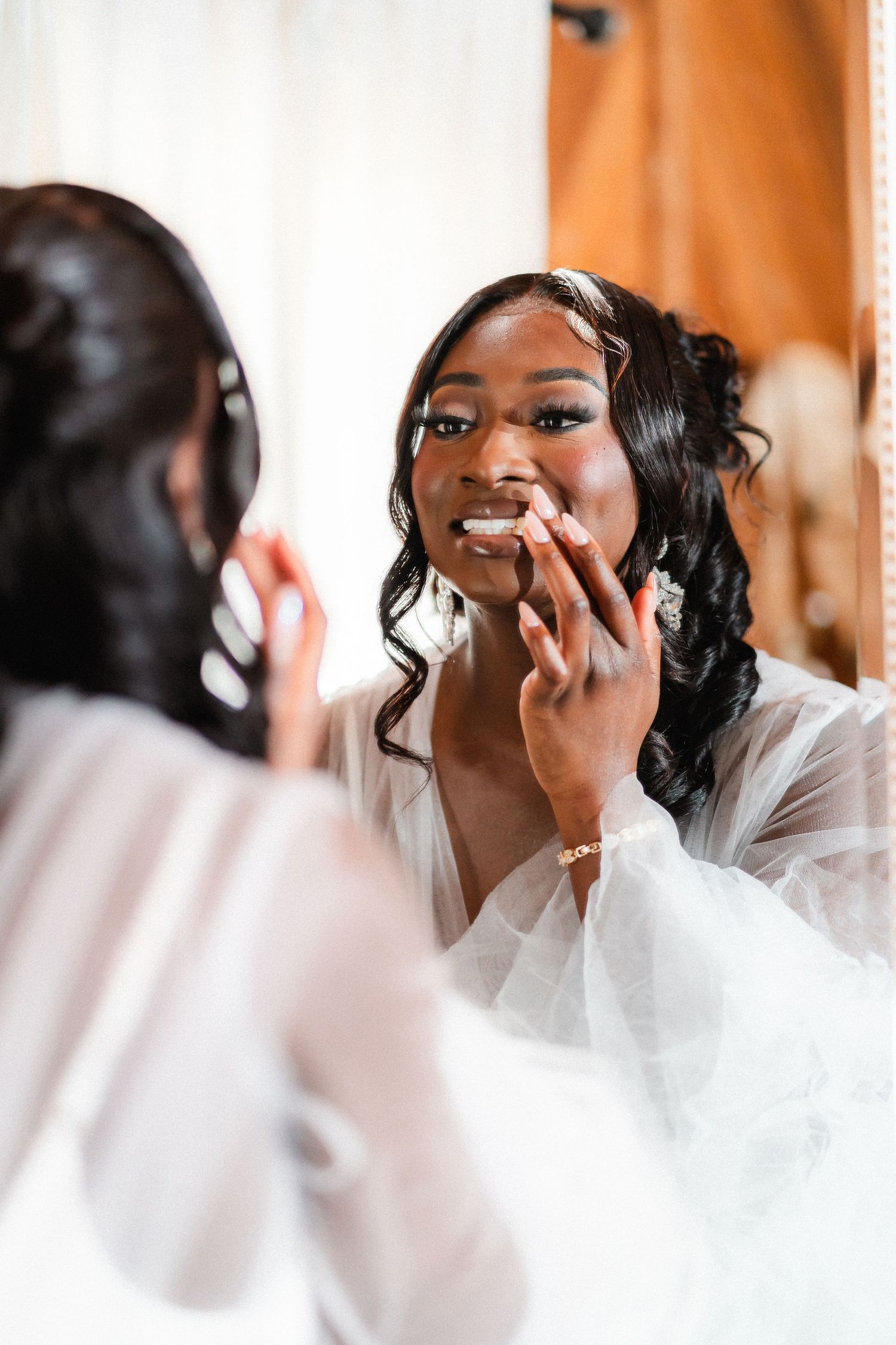 Reflection of bride applying makeup in mirror during wedding day preparations.