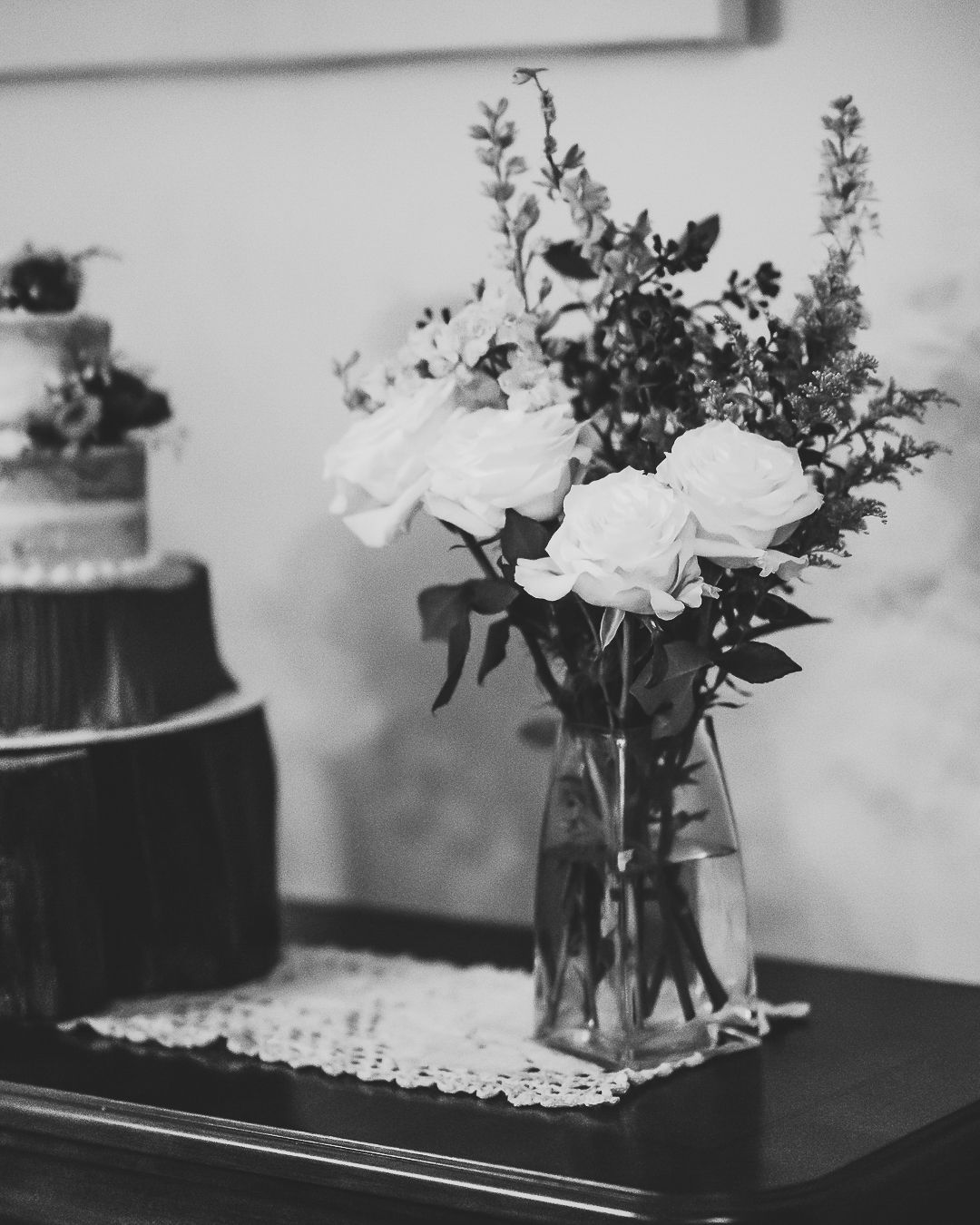 Black and white photograph of elegant white roses arranged in glass vases on a table.