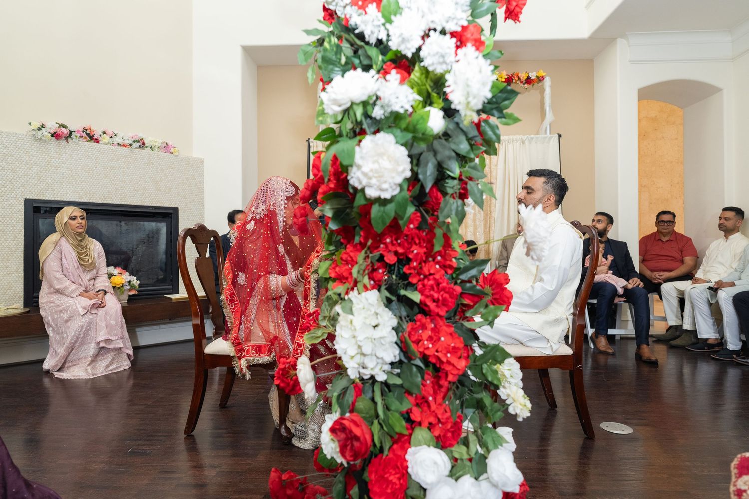 Wedding venue decorated with elegant red and white floral arrangements and white columns.
