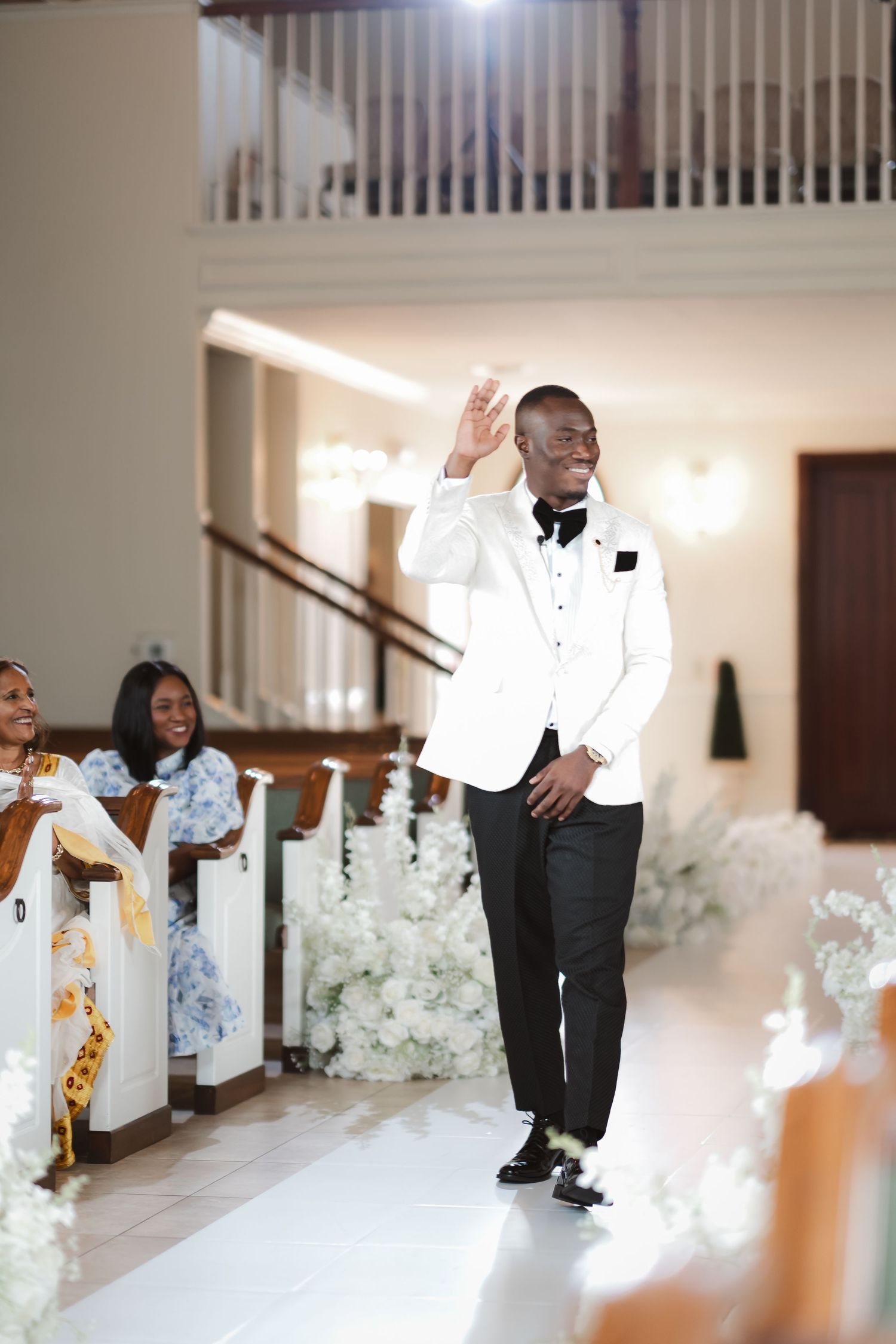 Wedding ceremony aisle decorated with white floral arrangements and elegant drapery.