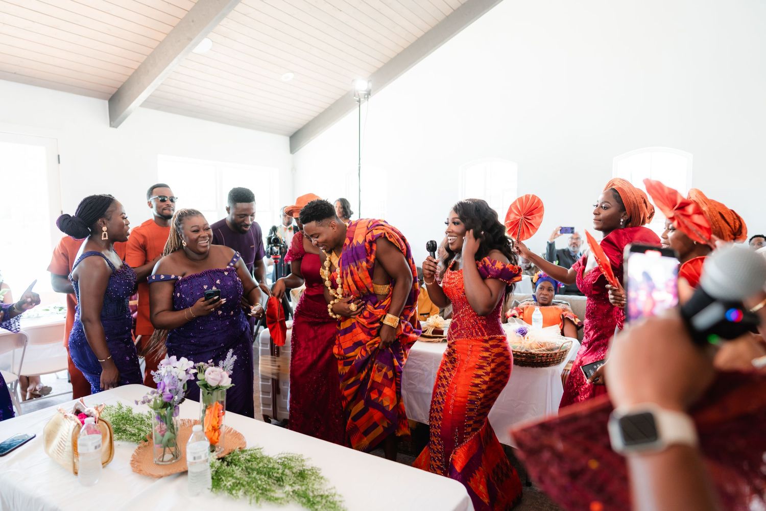 People gathered at a social event in a white room with exposed ceiling beams.
