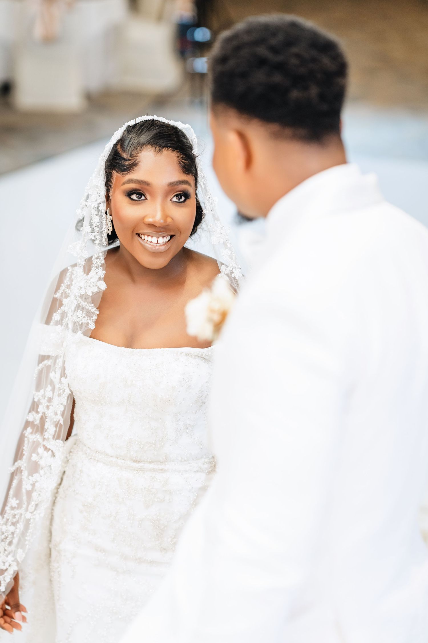 A bride in a fitted lace gown and veil shares an intimate moment during her wedding ceremony.