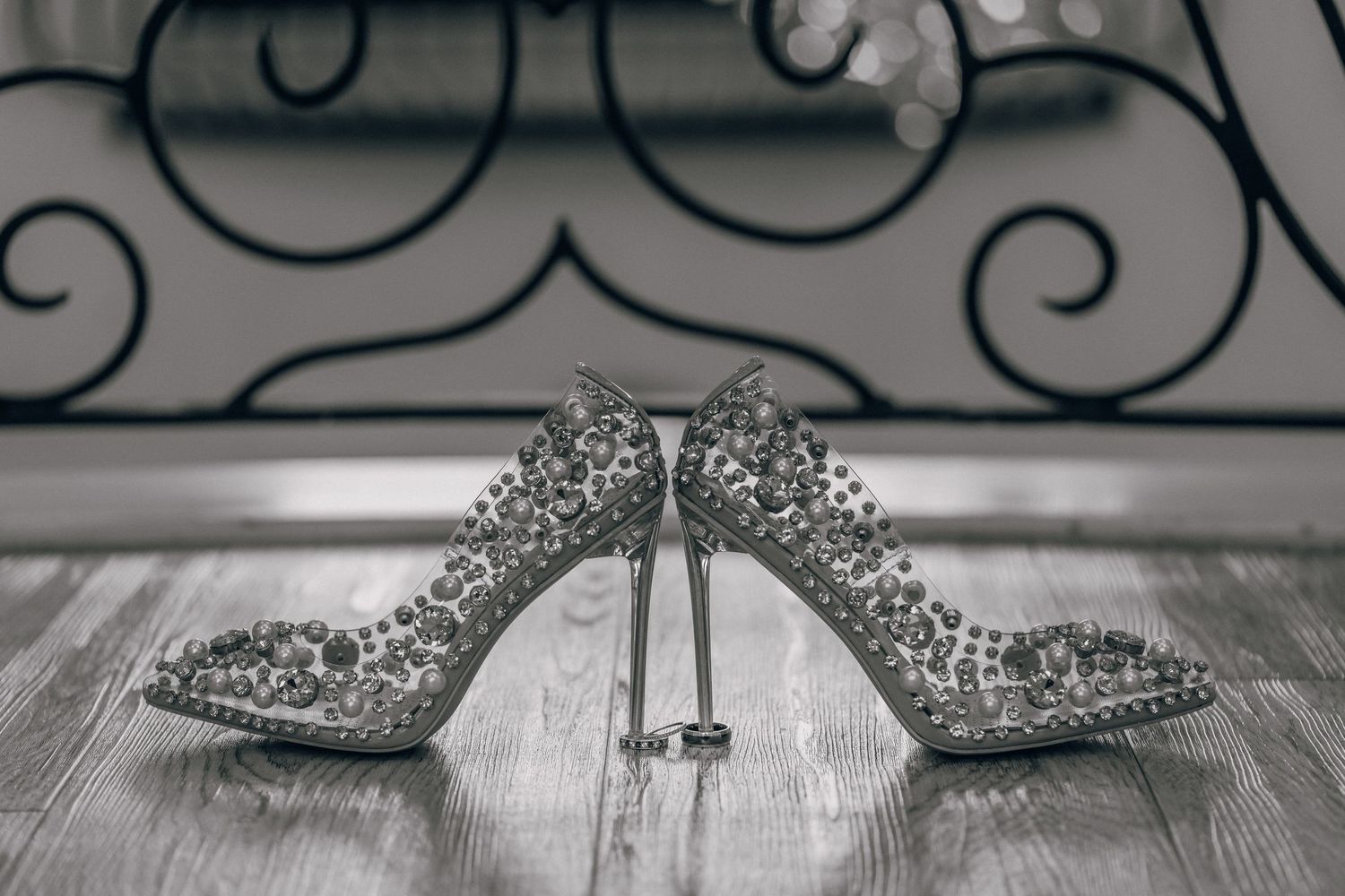 Crystal embellished bridal shoes displayed on a rustic wooden surface with ornate details.