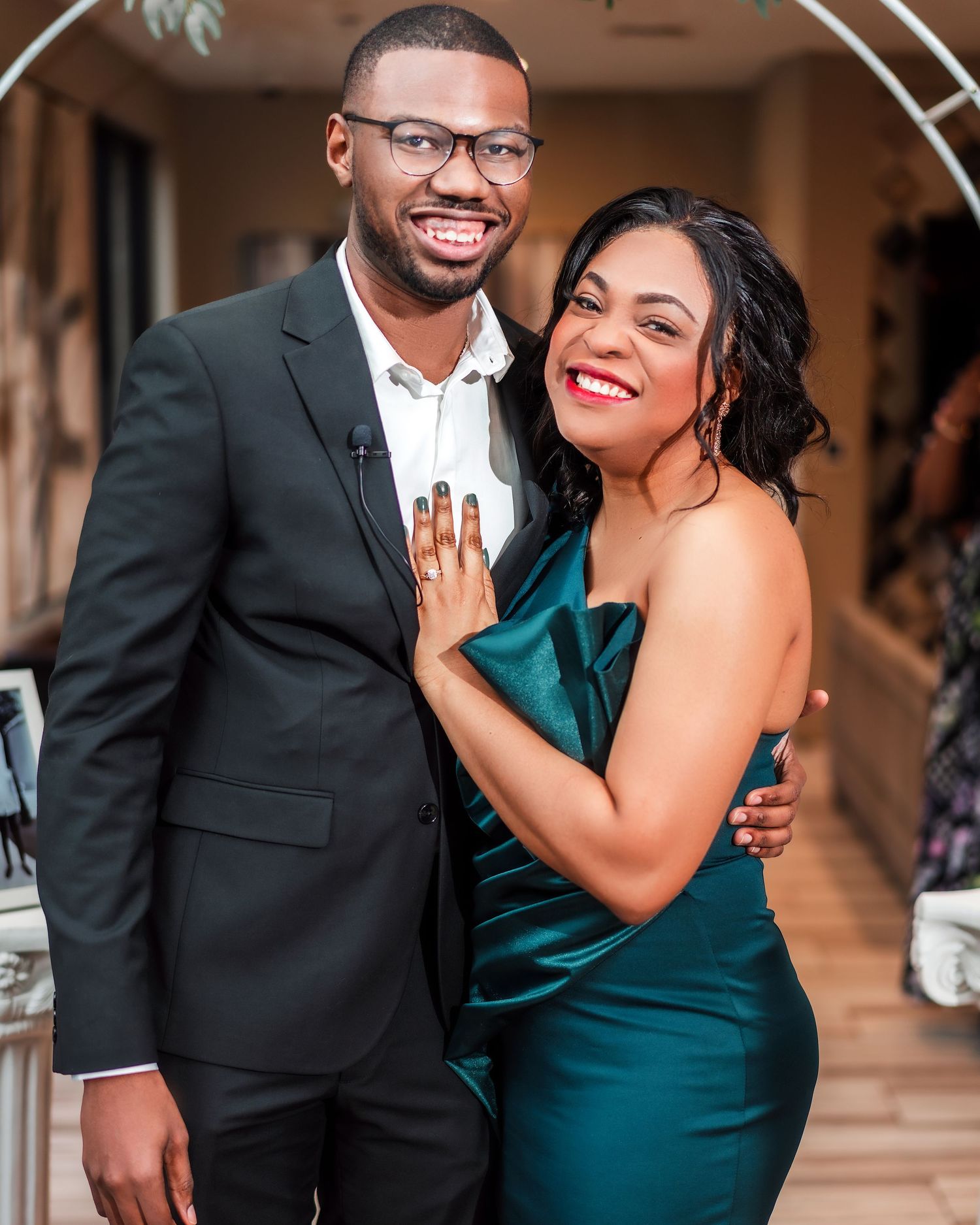 A joyful couple in formal attire share candid moments during a photo session in an elegant indoor setting.
