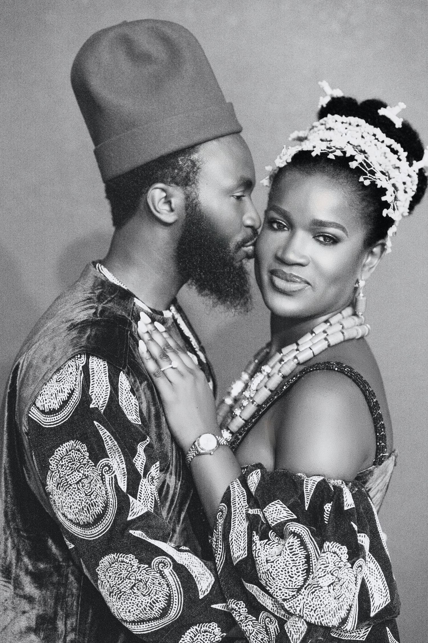 Black and white portrait of couple in matching traditional African attire with beaded accessories.