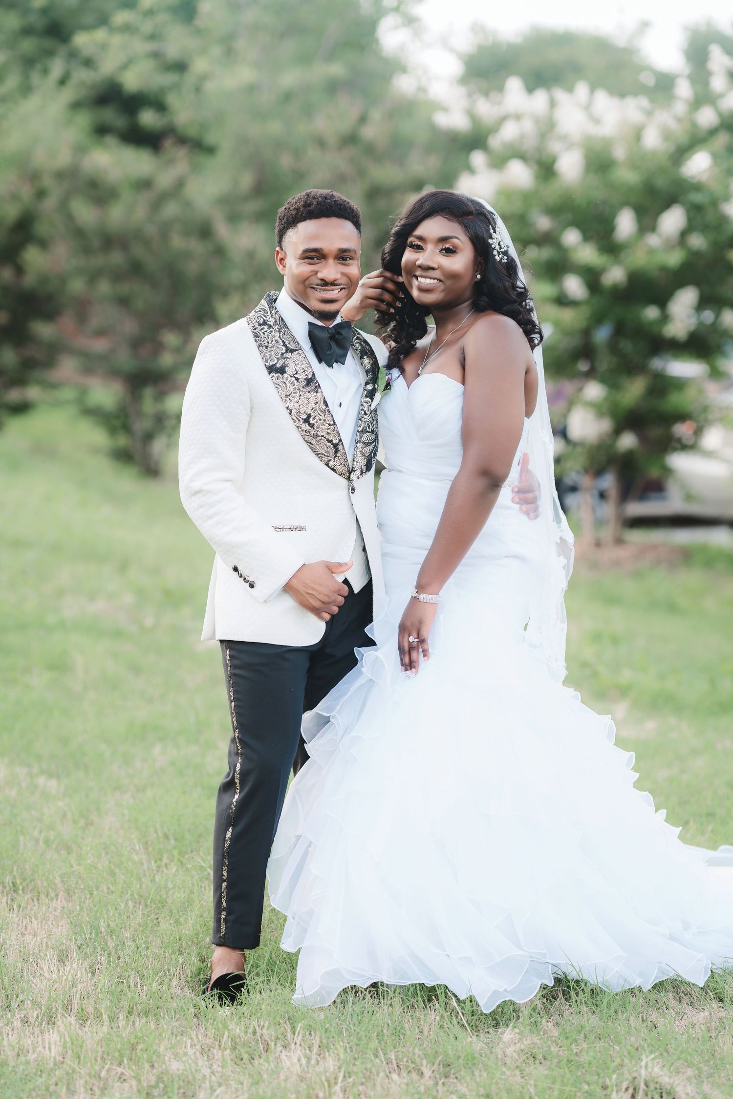 Romantic outdoor wedding photoshoot with couple in white attire posing in a garden setting.