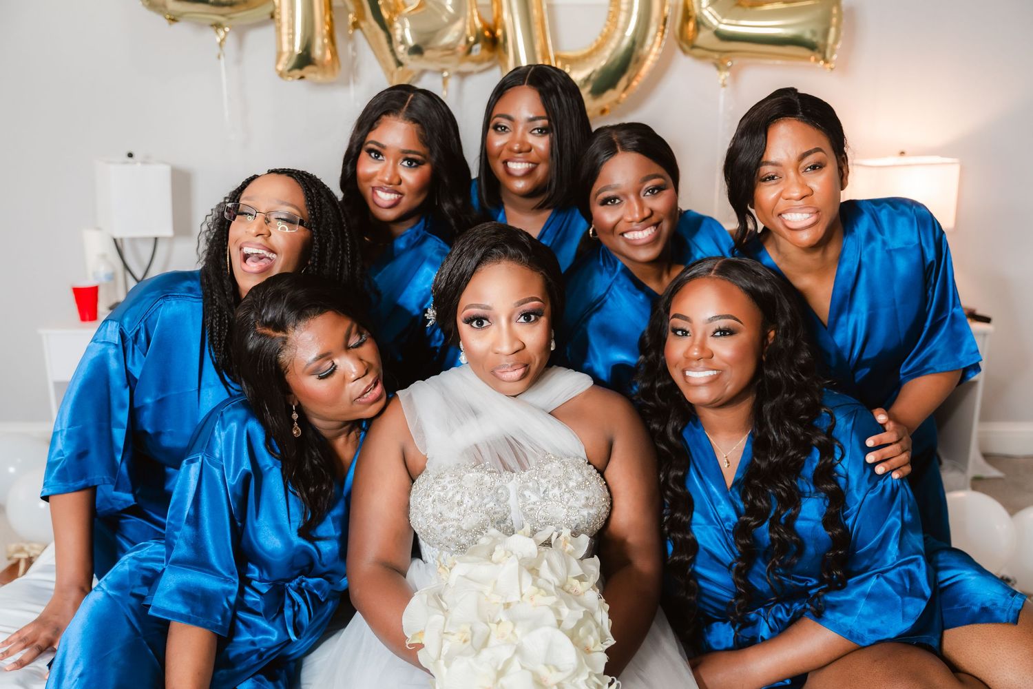 Bridesmaids in royal blue dresses pose with a bride in white holding a bouquet.