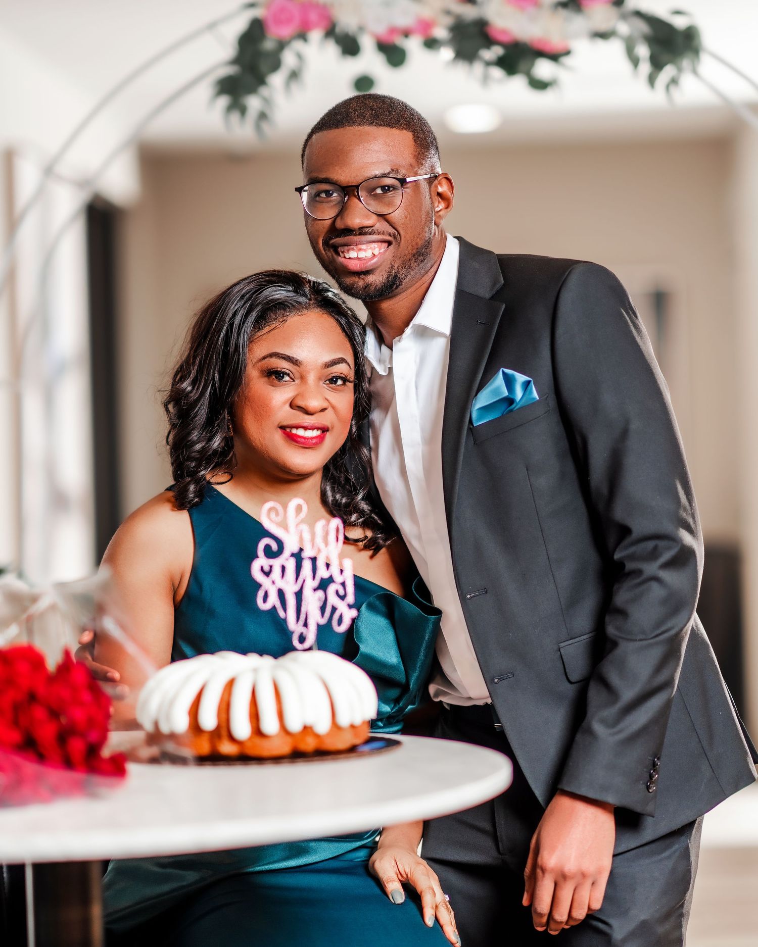 Engagement or wedding photoshoot with couple posing by decorative cake.