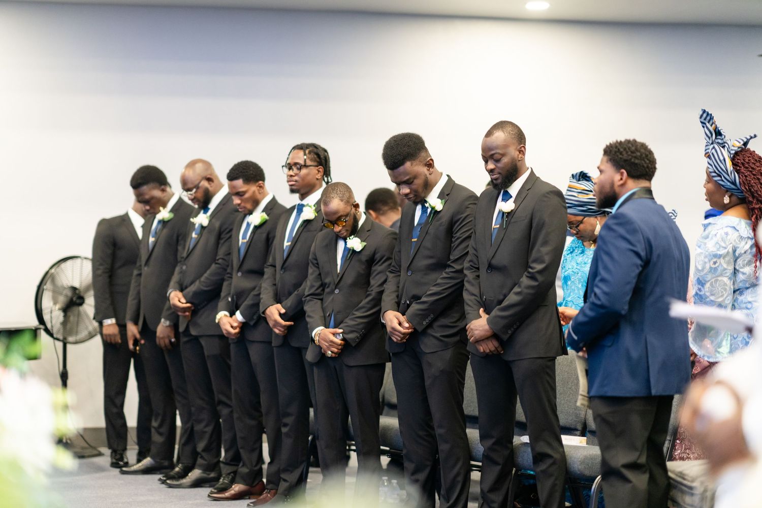 Business professionals in dark suits standing in a formal line formation at an event.