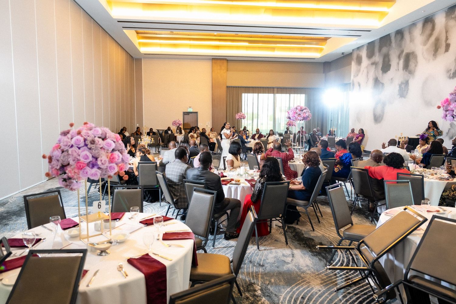 A large conference room setup with multiple round tables and chairs arranged for a formal dining or meeting event.