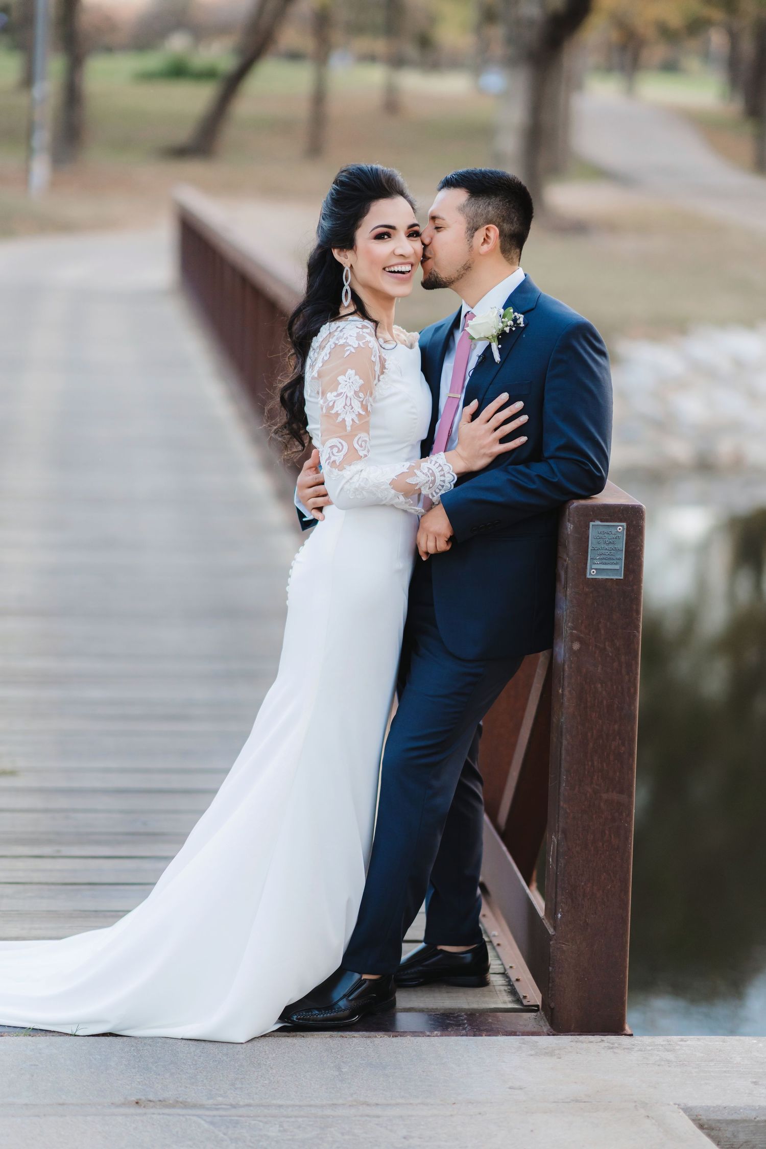 Romantic wedding couple sitting together on wooden dock by a lake.