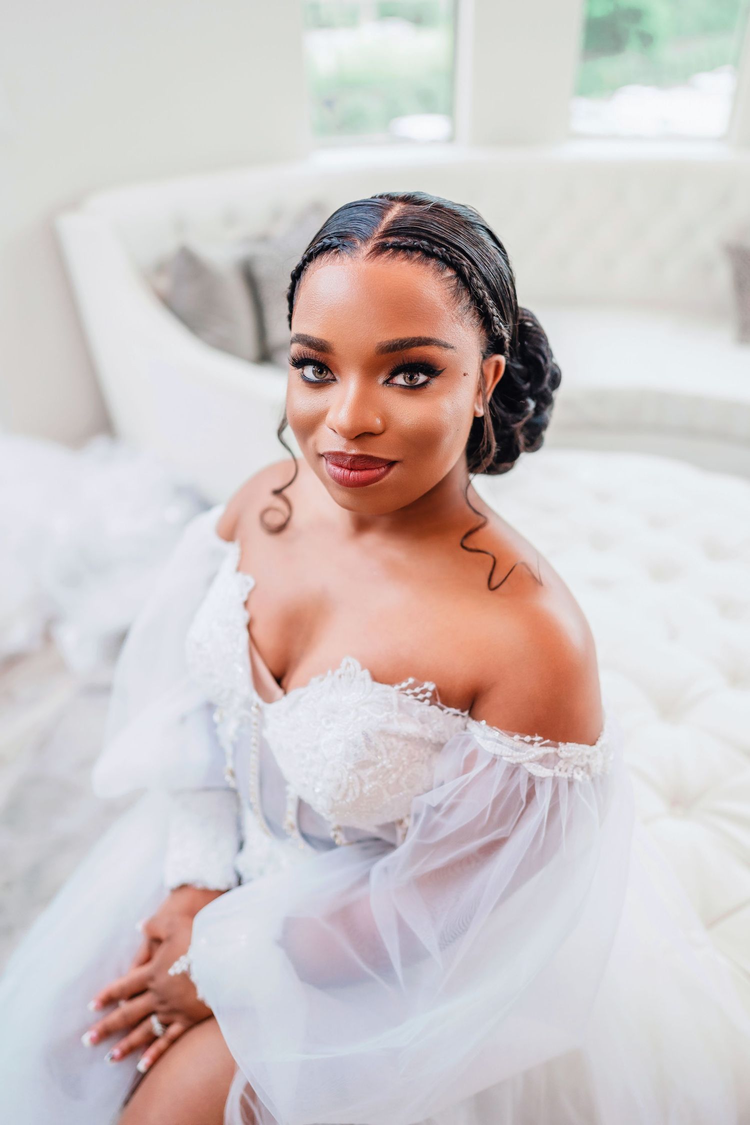 Elegant bridal portrait featuring a white off-shoulder wedding gown against a light background.