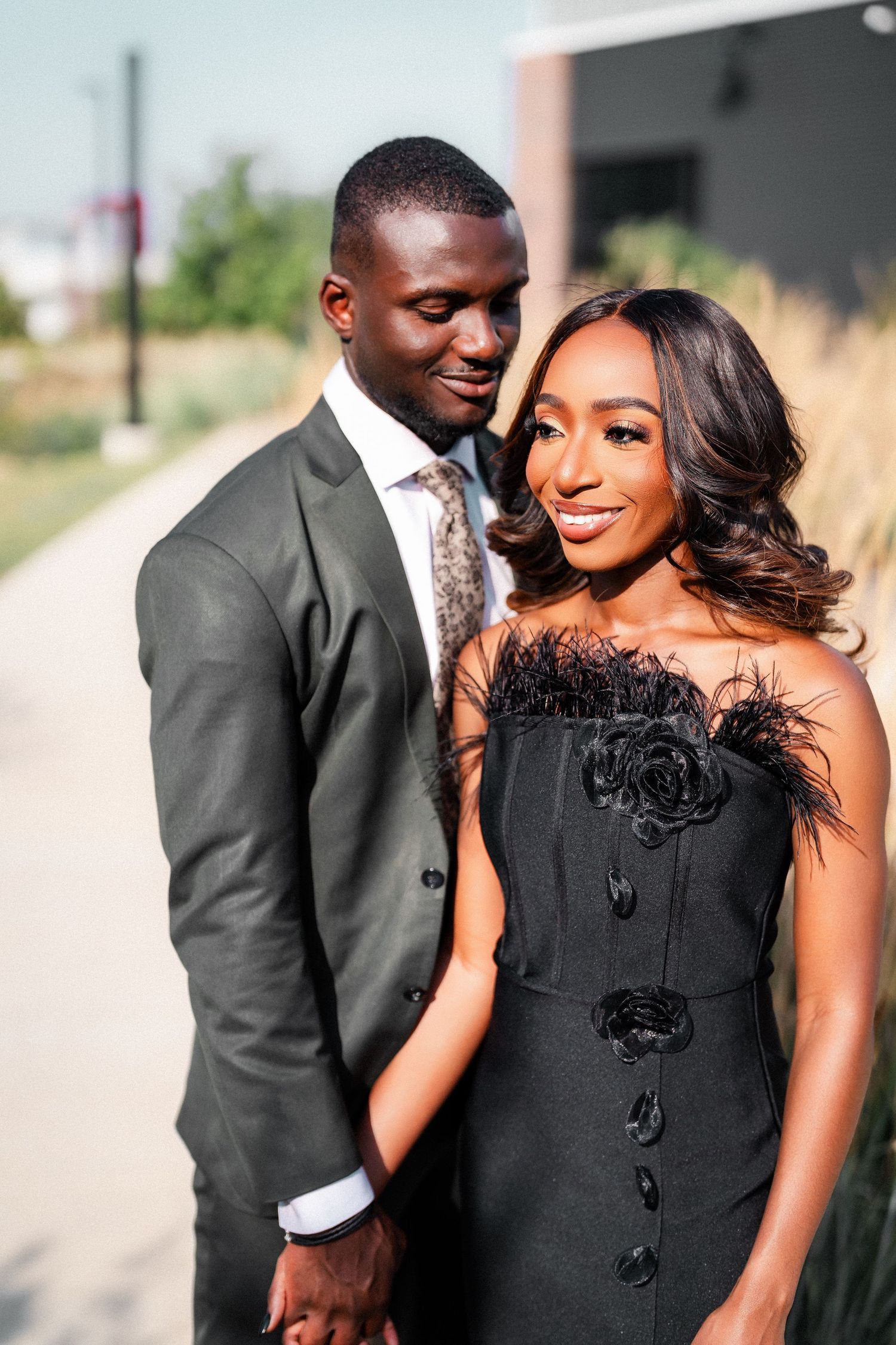 Couple in black and grey formal attire share romantic moments during outdoor photo session.