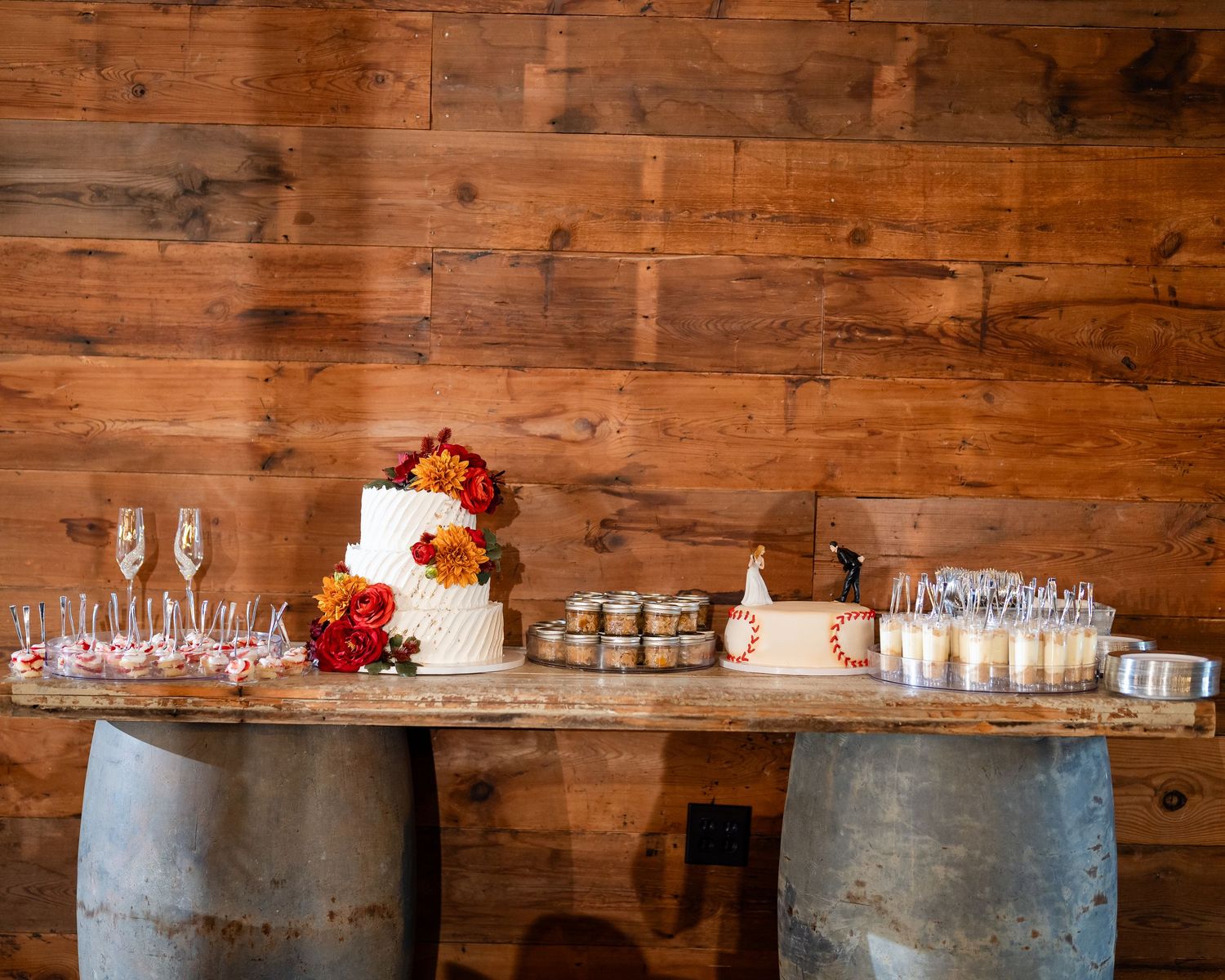 Rustic wedding reception setup with wooden walls and metal drink stations.