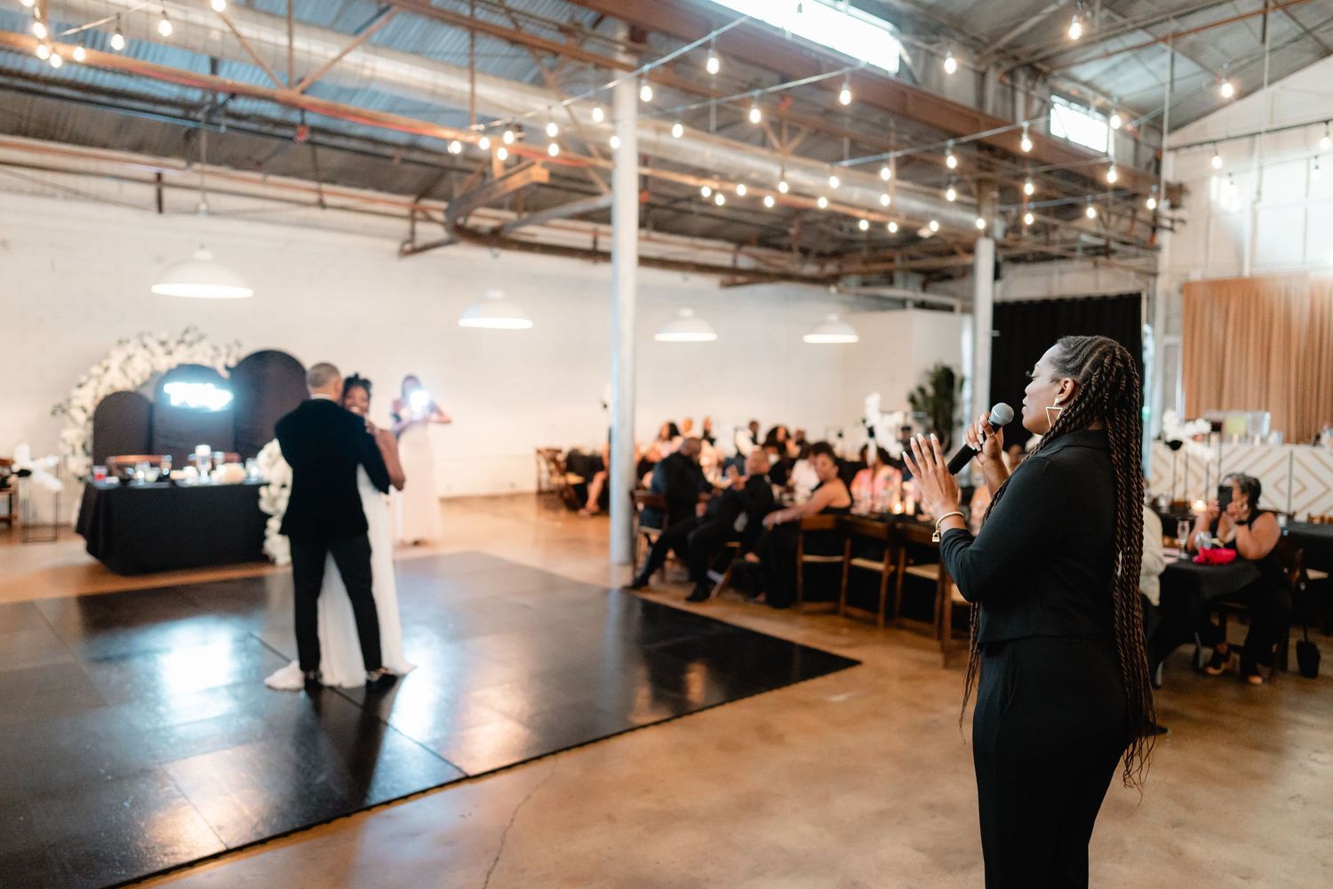 Industrial wedding venue with string lights shows guests seated for ceremony.