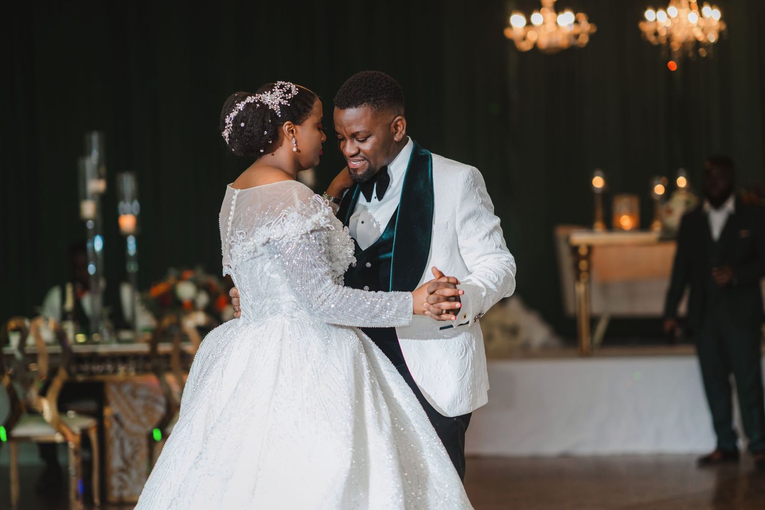 A romantic first dance moment at an elegant wedding reception with chandeliers.