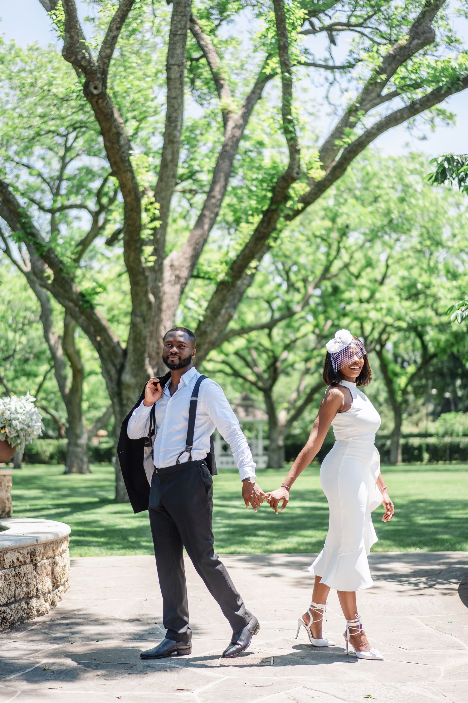 Joyful wedding celebration with dancing and laughter in a lush outdoor park setting.