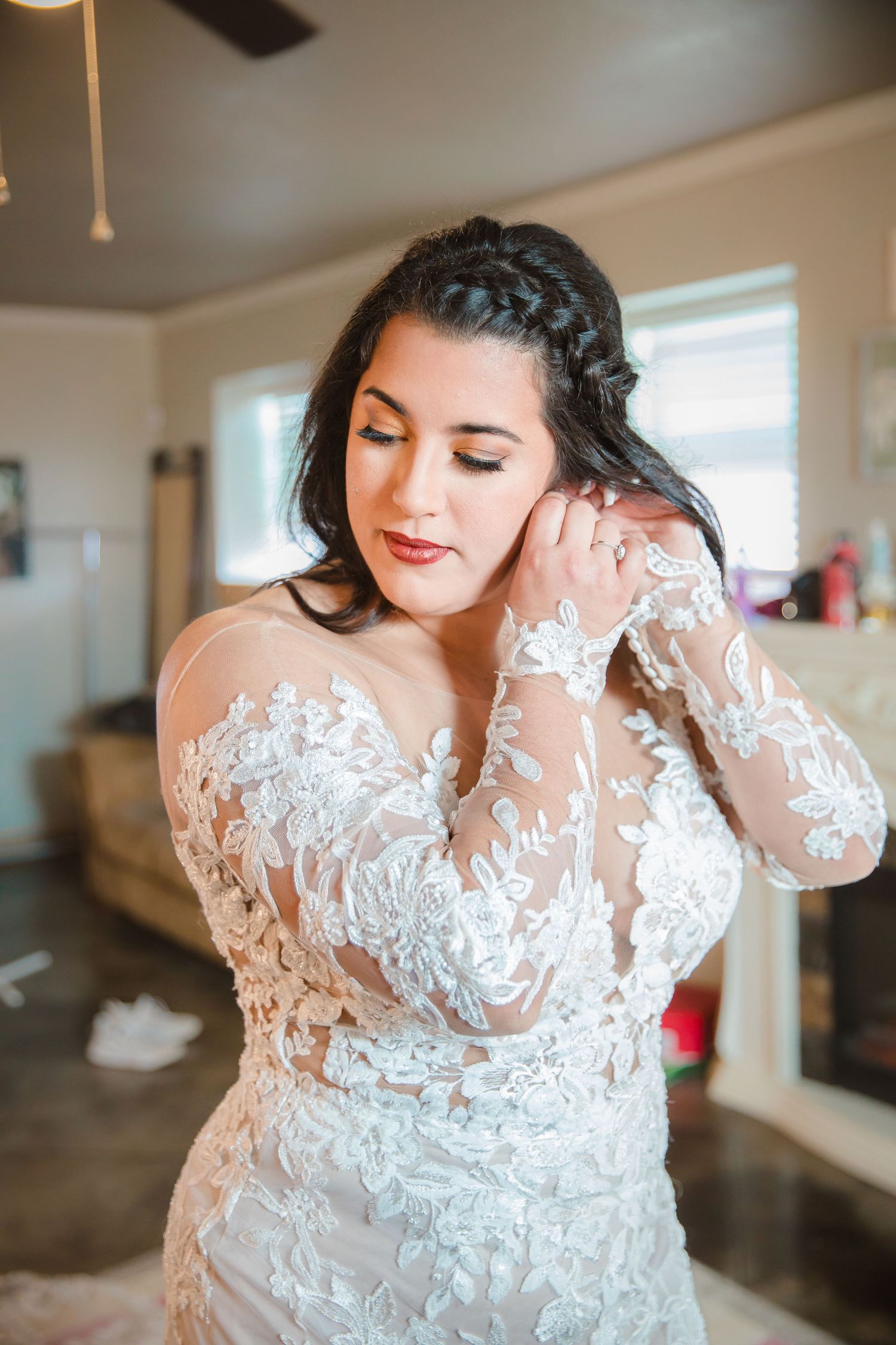 Close-up details of a delicate white lace wedding dress with intricate floral embroidery and sheer sleeves.