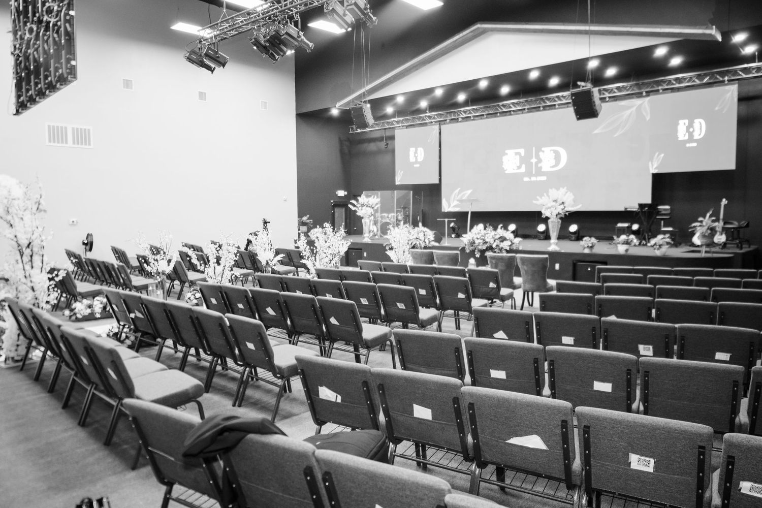 Conference attendees seated in rows of chairs in a large auditorium with modern lighting and presentation screens.