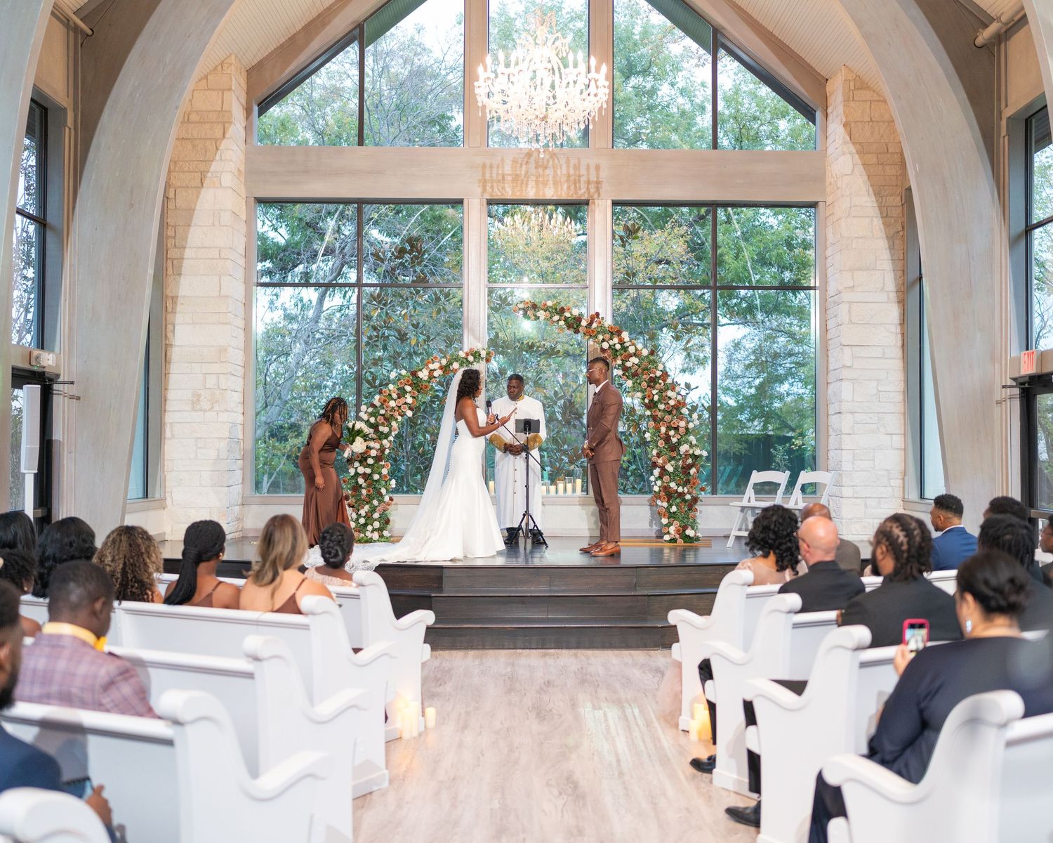 Panoramic view of a modern chapel wedding venue with arched windows and decorative floral arrangements.
