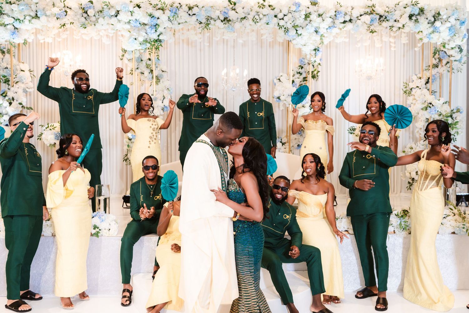 Wedding party celebrating with energetic poses in front of a floral backdrop.
