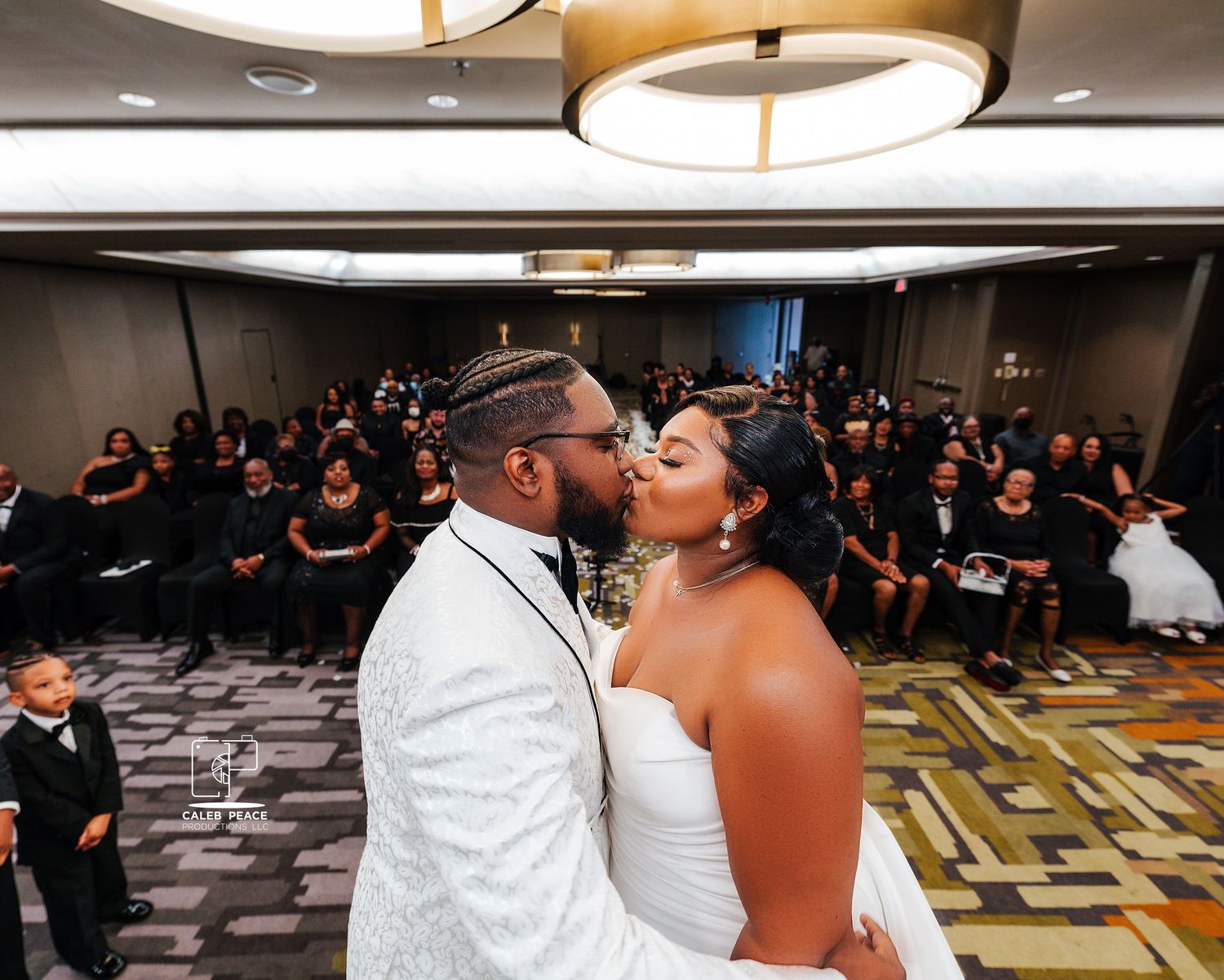 Newlyweds share their first dance under modern circular lighting fixtures.
