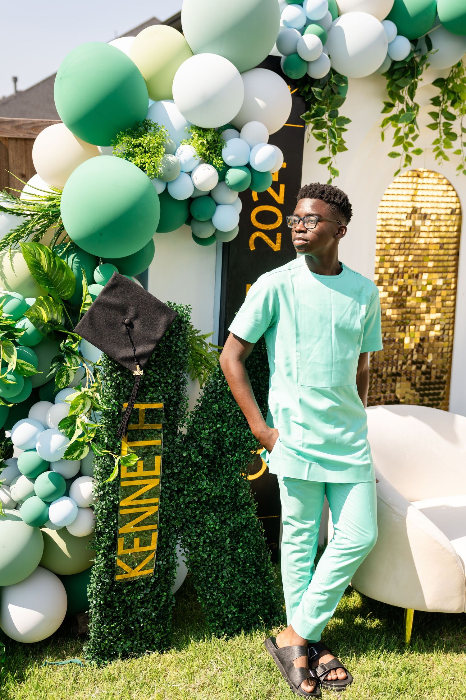 Mint green balloon arch and decorative display with white accents creates an elegant outdoor party setting.