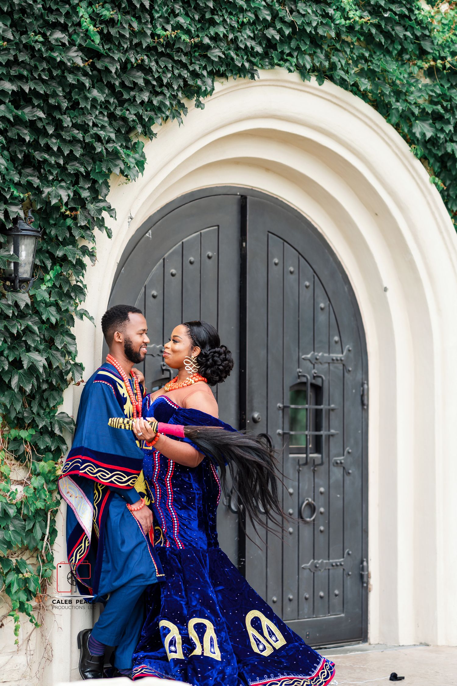A romantic engagement photo series in front of an arched doorway with ivy and Spanish-style architecture.