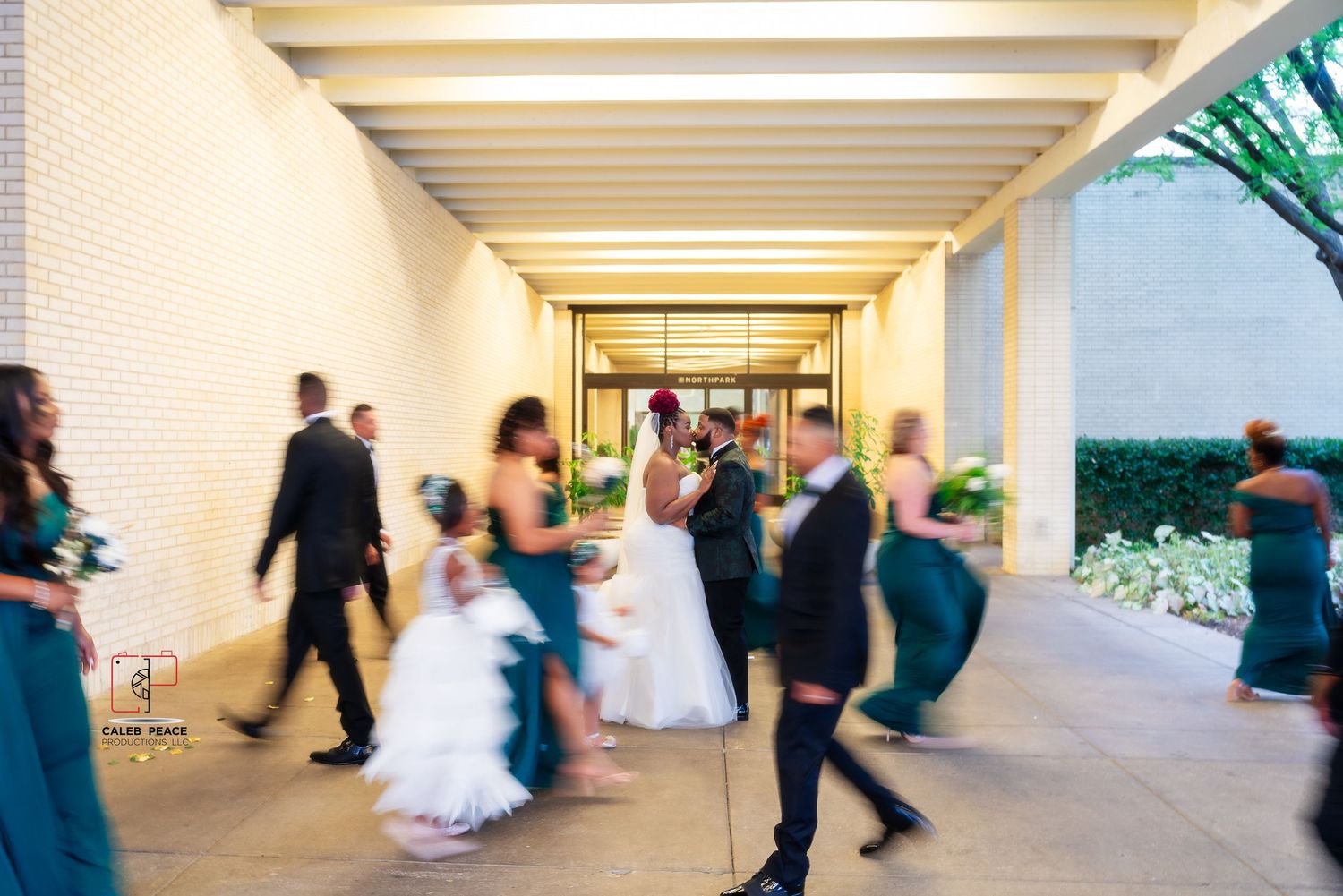 Guests dancing in a covered outdoor venue with white columns and natural lighting.