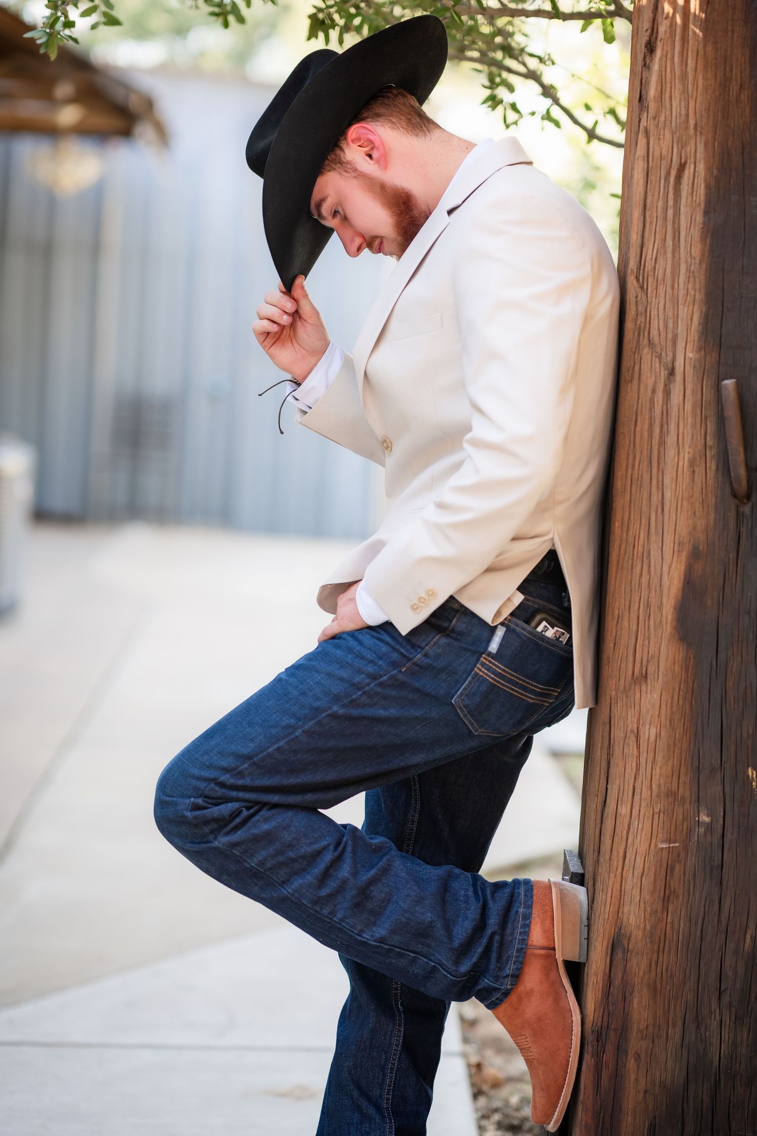 Casual western-style portrait with denim and white attire against wooden posts.