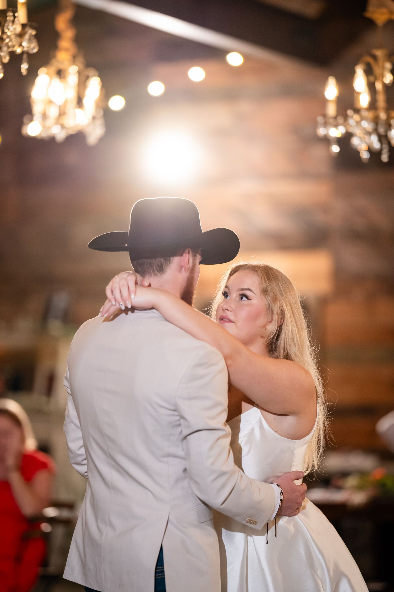 Romantic dance sequence under warm chandelier lighting at a rustic wedding reception.