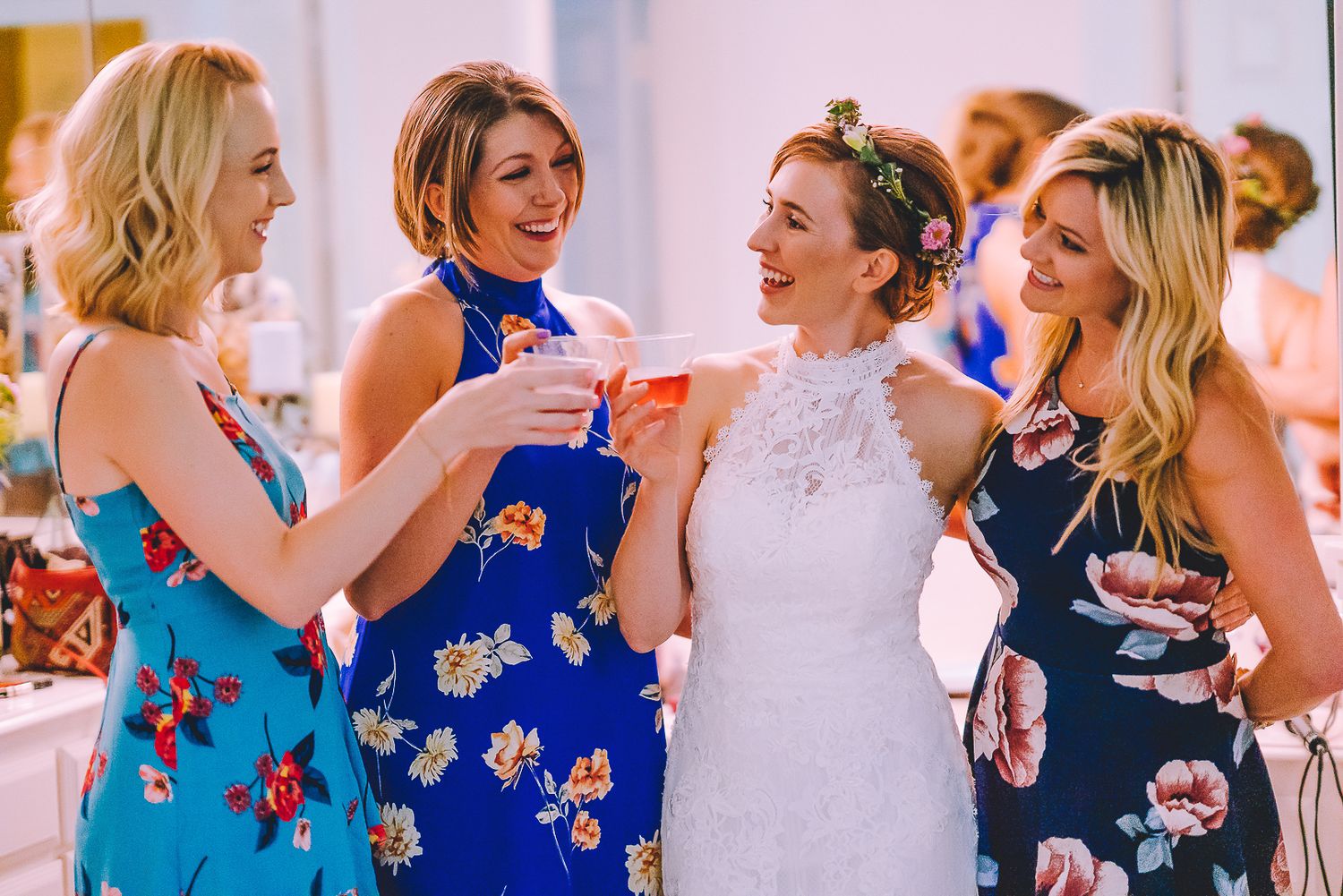 Wedding party wearing coordinated blue floral dresses celebrating together at a bright indoor reception.